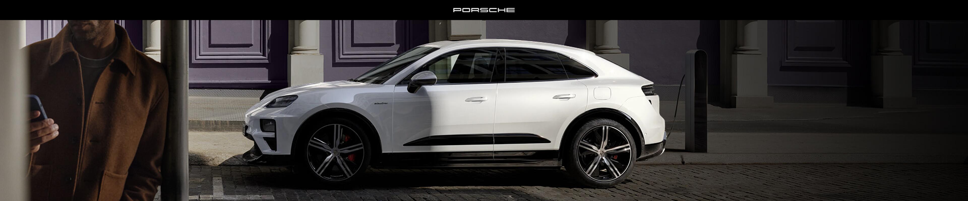 Profile view of a Porsche Macan 4 Electric in White charging at a curbside station.
