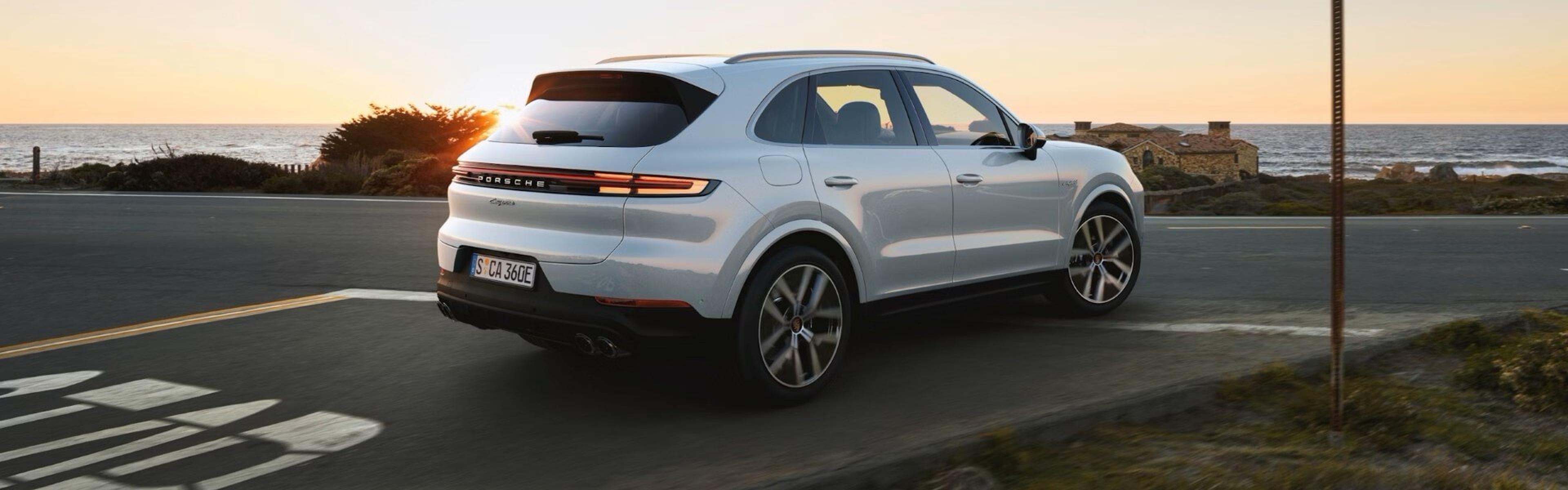 2026 Porsche Cayenne E-Hybrid In Carrara White Metallic Driving On A Country Road Banner