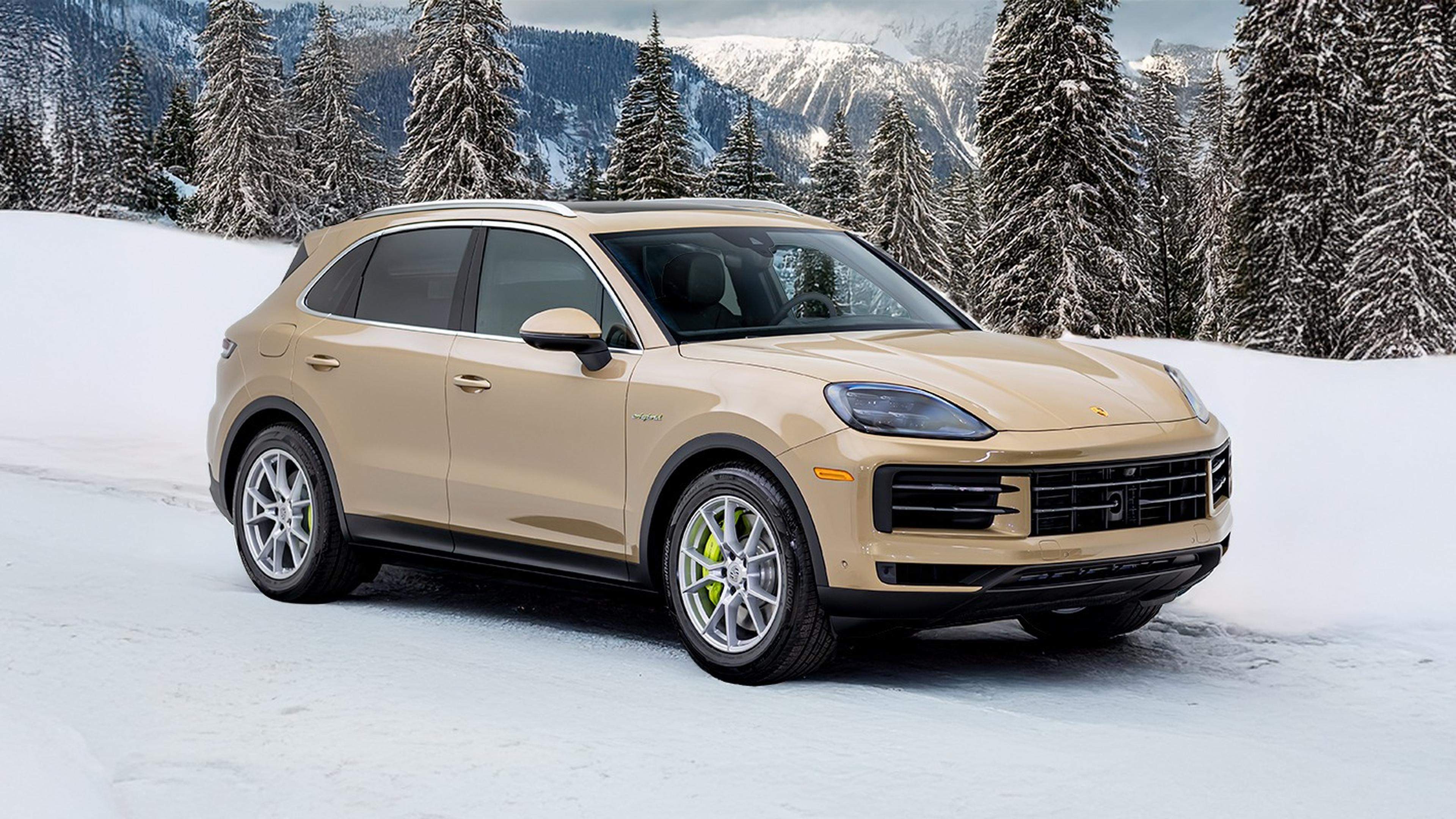 A beige Cayenne parked on a snowy landscape with snow-covered trees and mountains in the background.