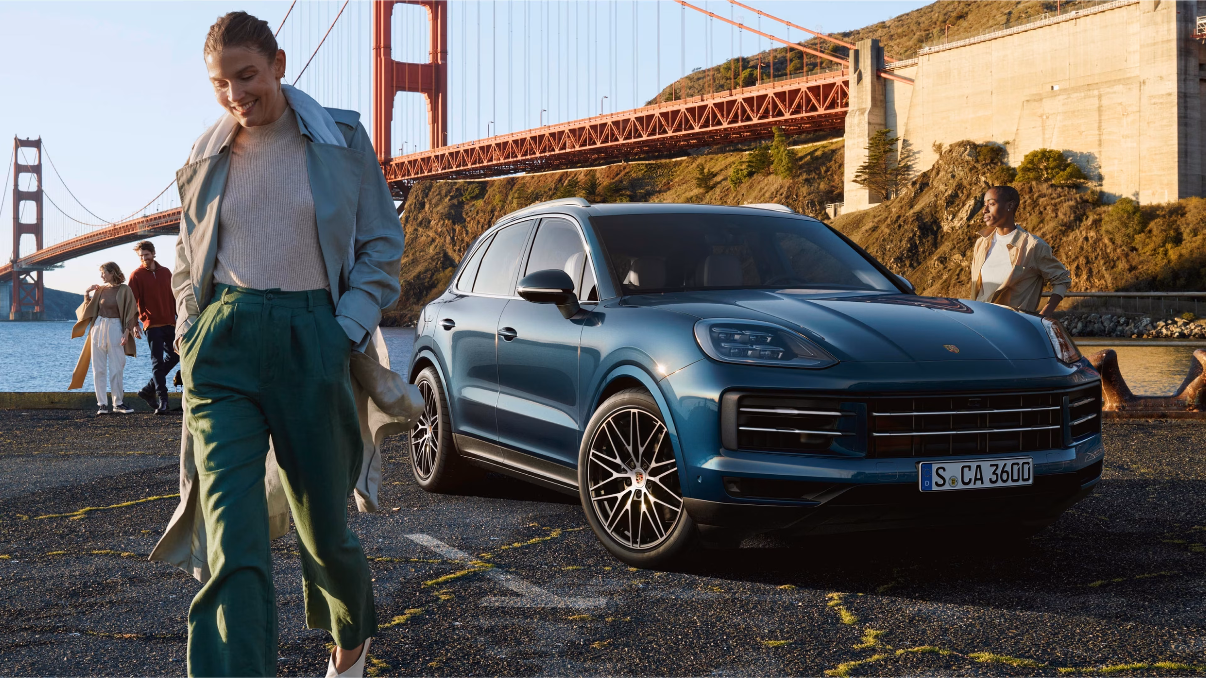 Blue Porsche Cayenne displaying its traditional SUV silhouette near a waterfront bridge