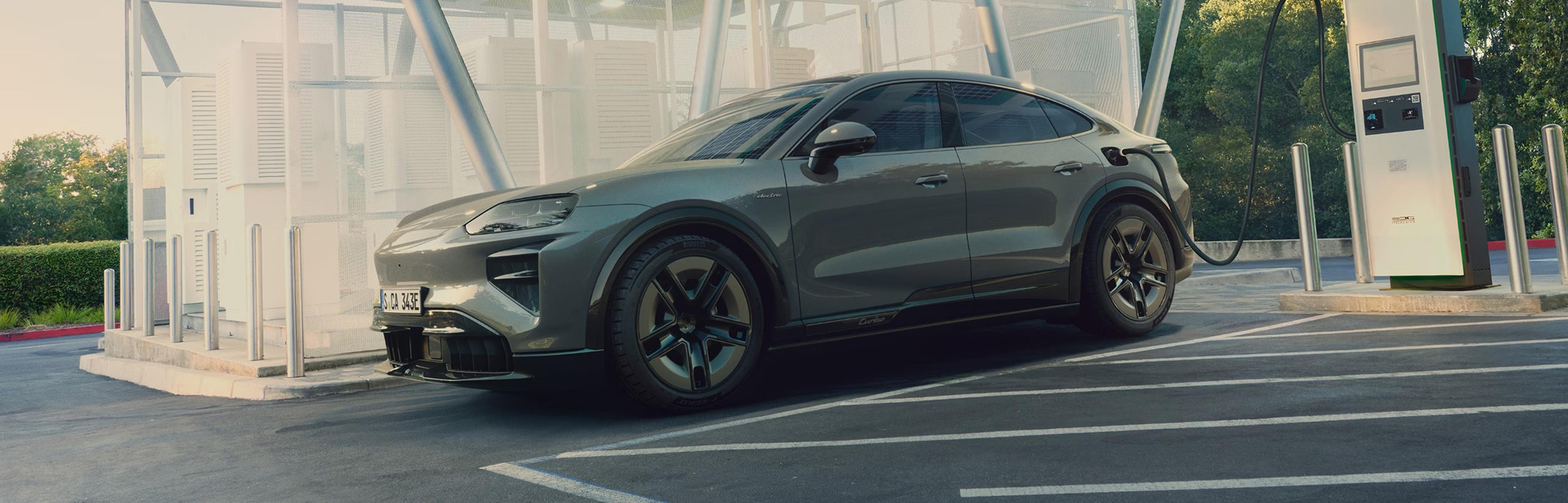 The 2027 Porsche Cayenne Coupe Electric parked and plugged into a charger at a charging station