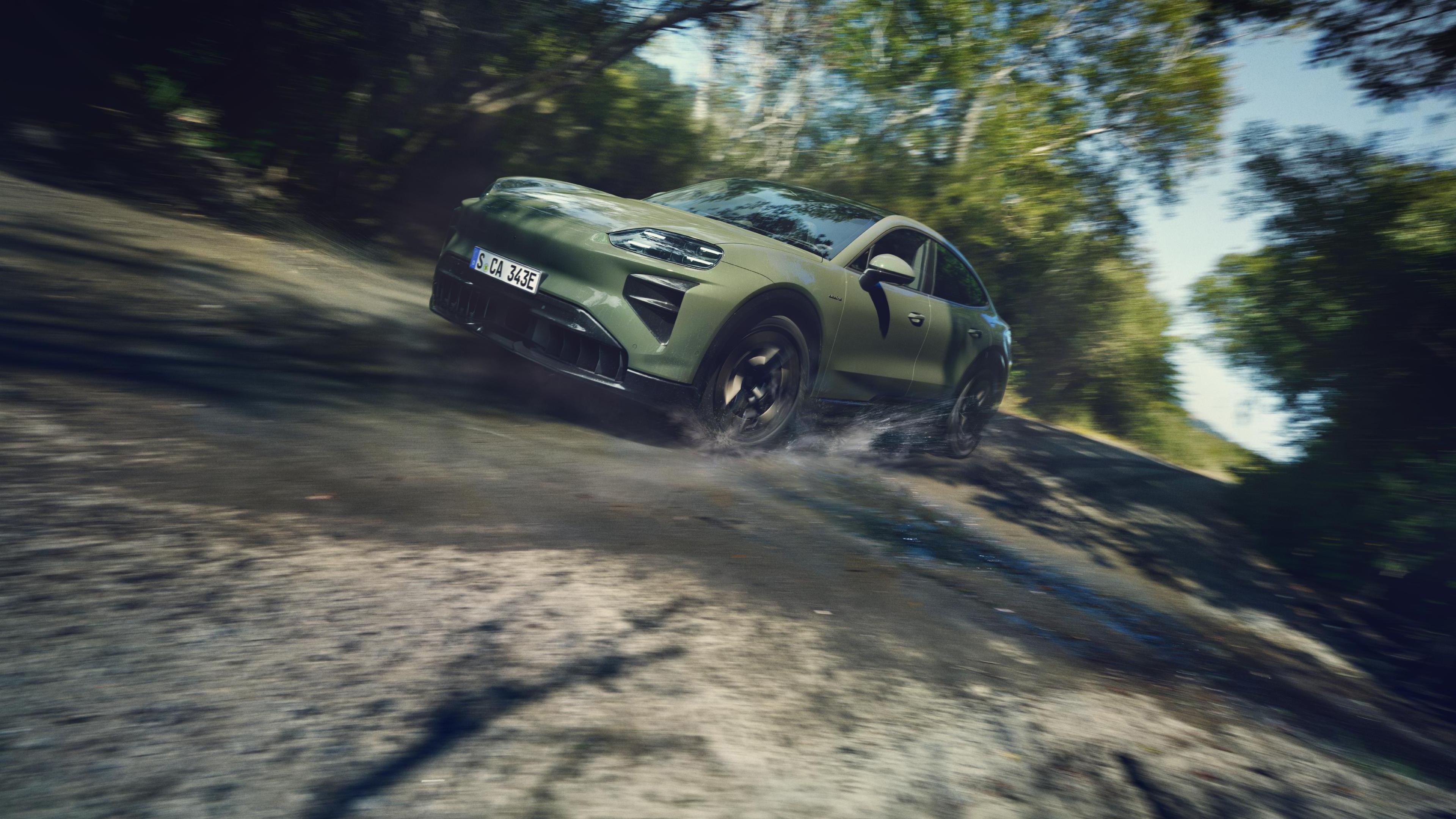 Porsche Cayenne Turbo Coupé Electric in Monteverde Metallic driving along a dirt road.