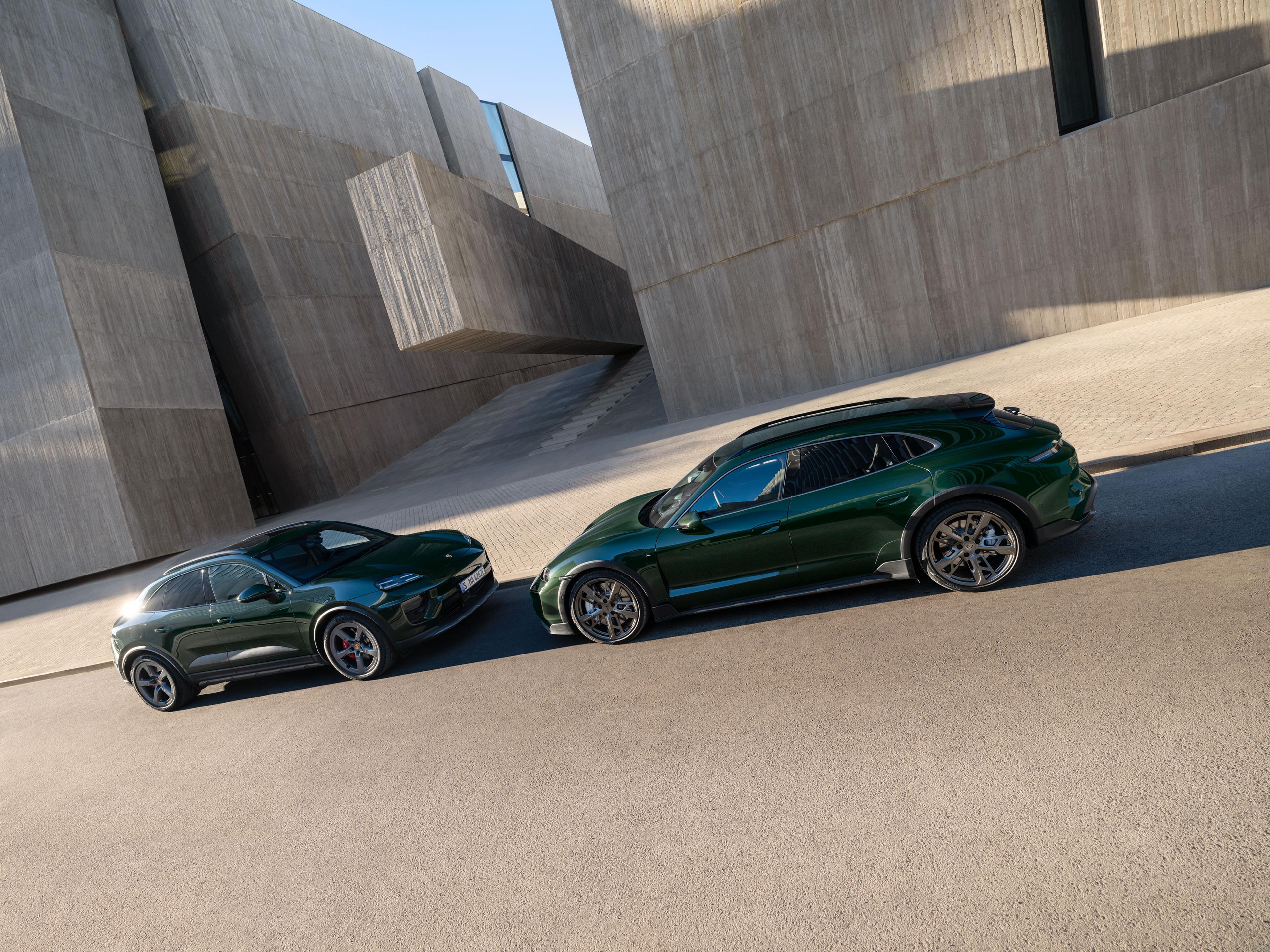 Zwei grüne Sportwagen parken auf einer Kopfsteinpflasterstraße; sie stehen schräg zueinander und präsentieren ihr elegantes Design sowie ihre Leichtmetallfelgen.