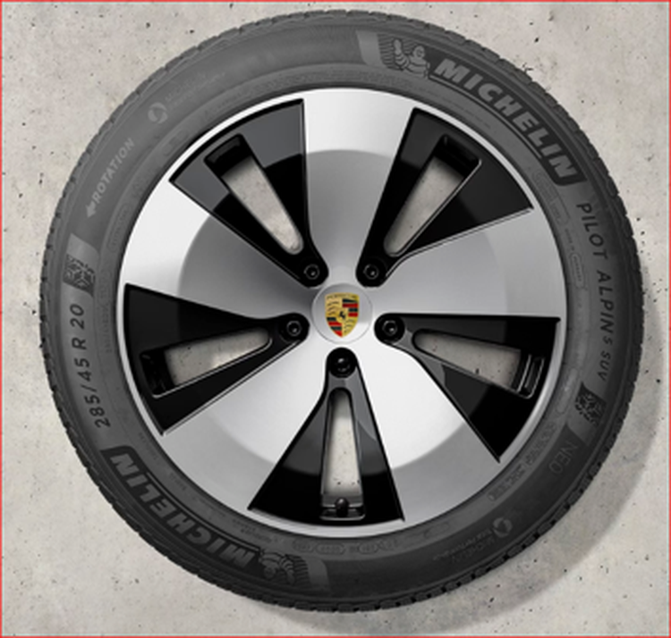 A black and silver Porsche Macan Electric wheel featuring the Porsche logo at the center, mounted with Michelin Pilot Alpin SUV tire.
