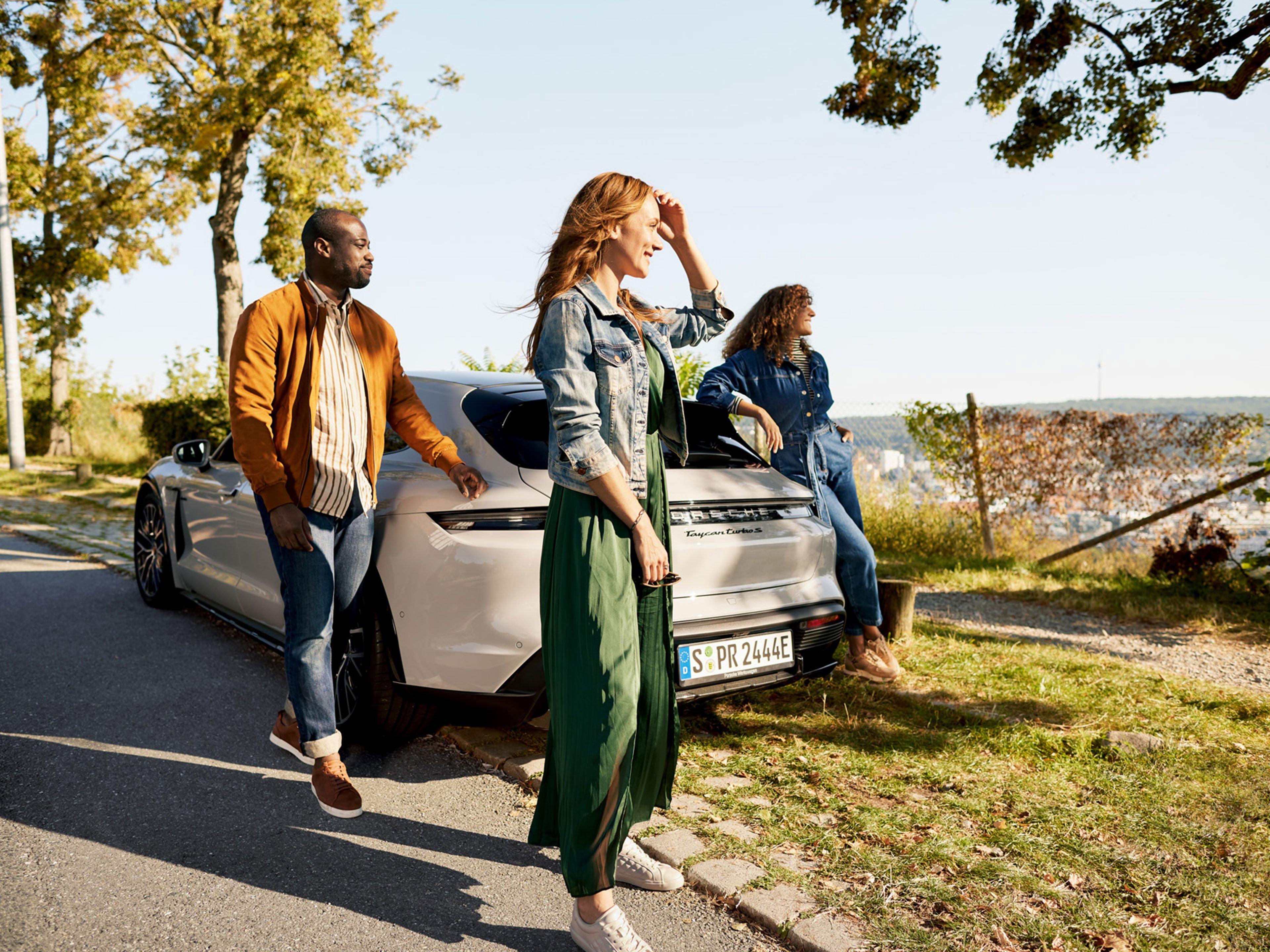 Eine Gruppe steht um einen Sportwagen in der Natur.