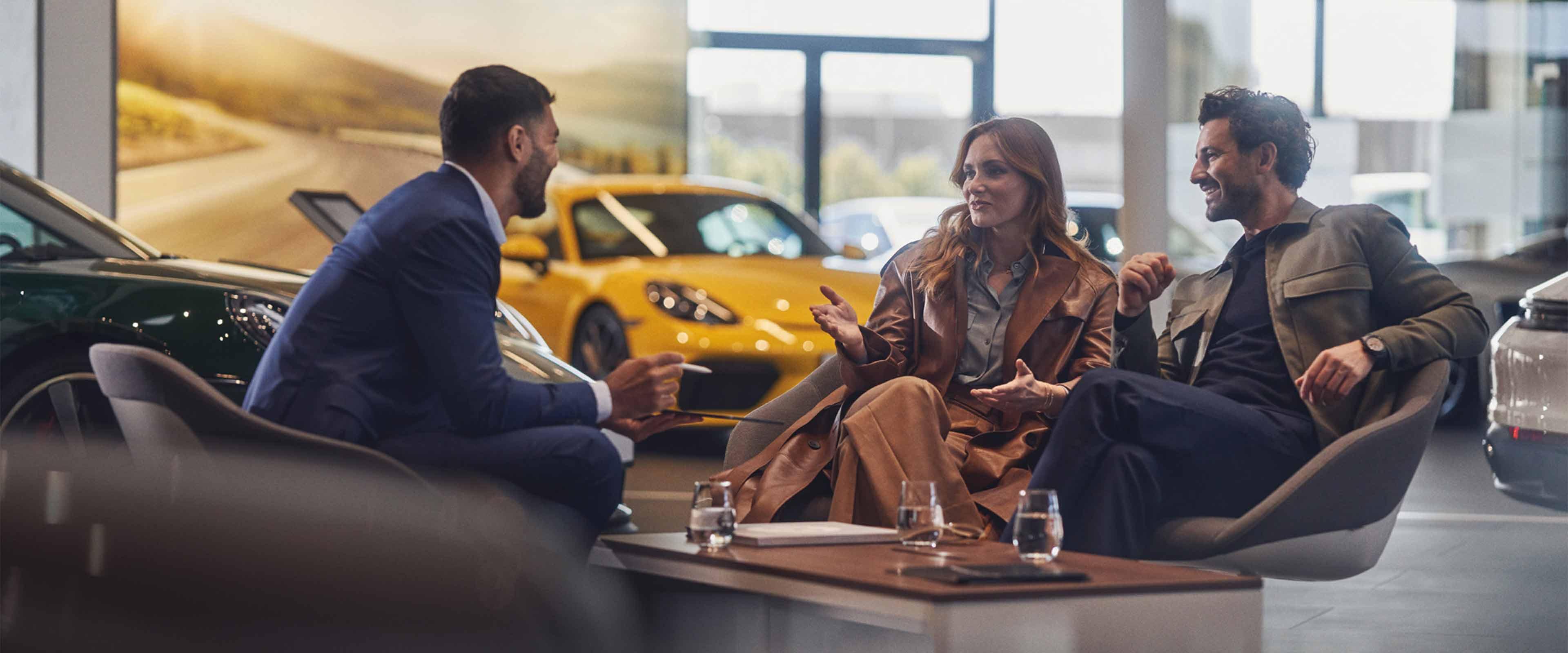 A couple discussing with a salesman in a car showroom