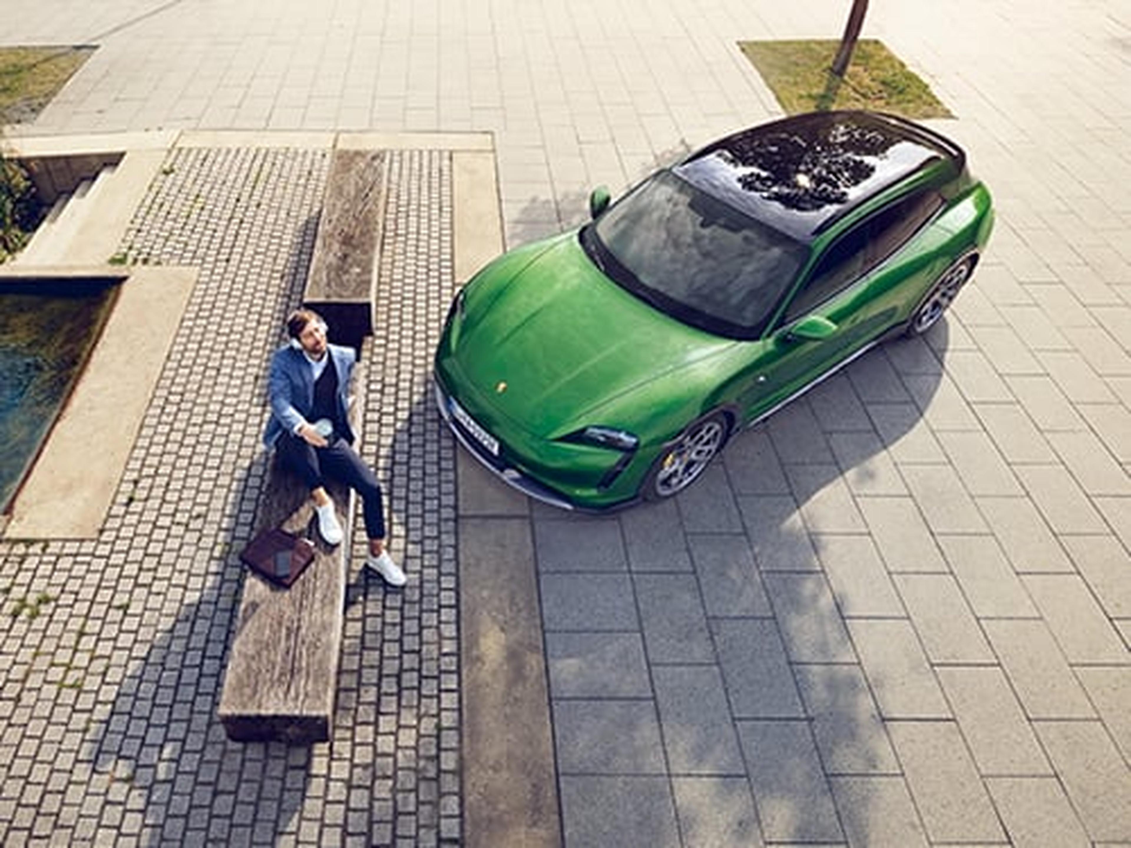 Ein Porsche Kunde geniesst die Sonne neben seinem Porsche Sportwagen.