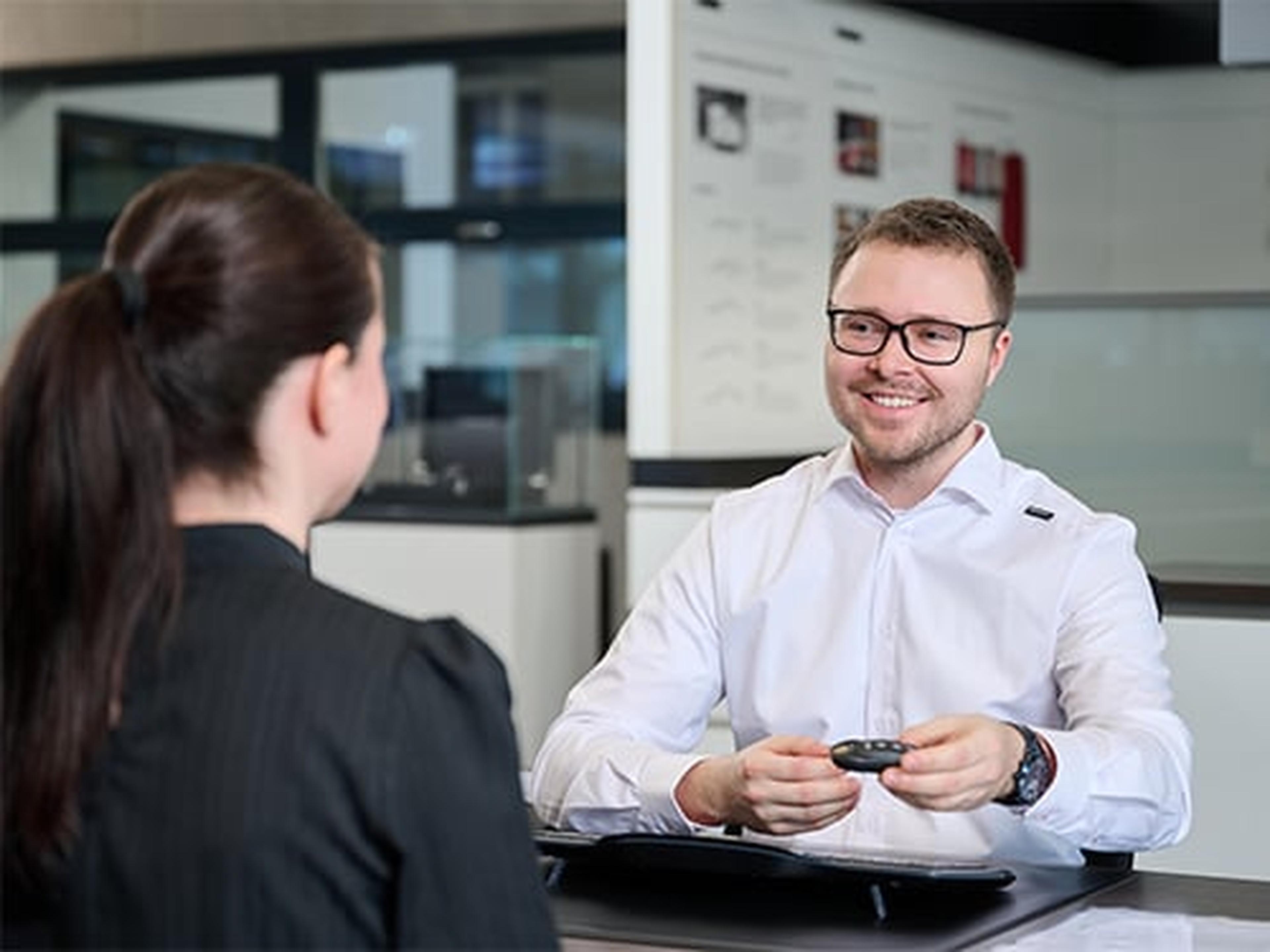 Ein Porsche Service Mitarbeiter führt ein Kundengespräch.