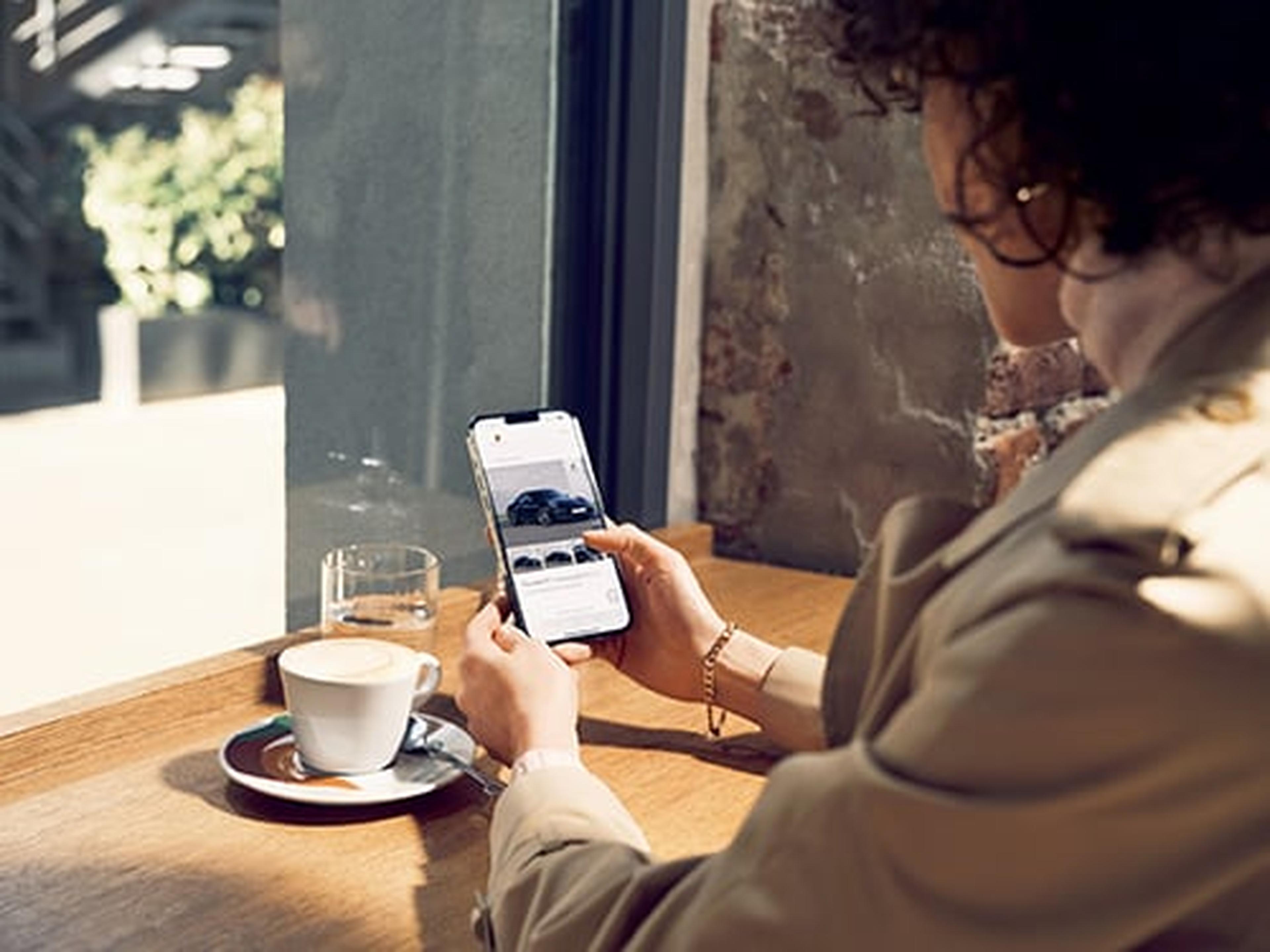 Eine Porsche Kundin schaut sich Porsche Approved Angebote auf ihrem Mobilgerät an.
