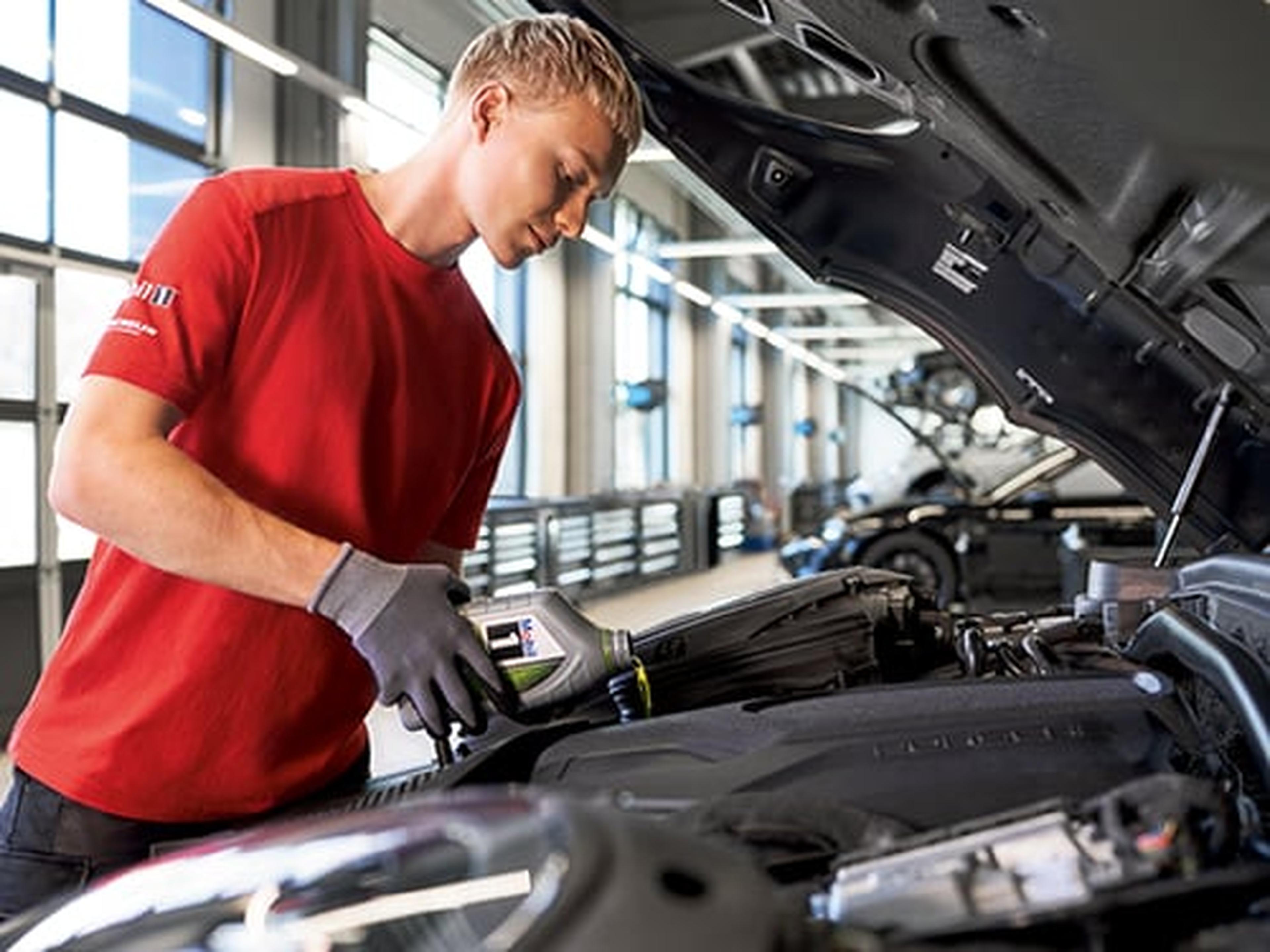 Mann prüft den Motor eines Autos in einer Werkstatt.