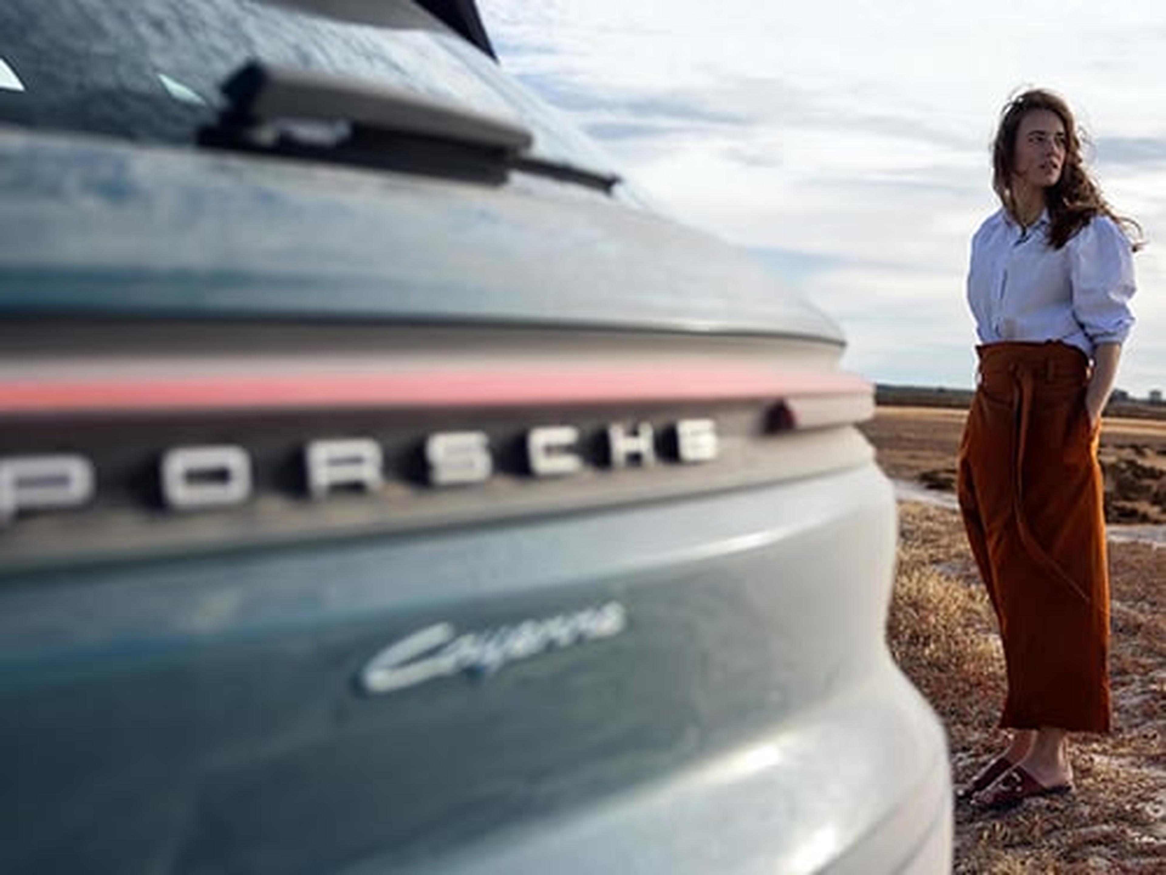 Eine Frau steht neben einem Porsche Cayenne.