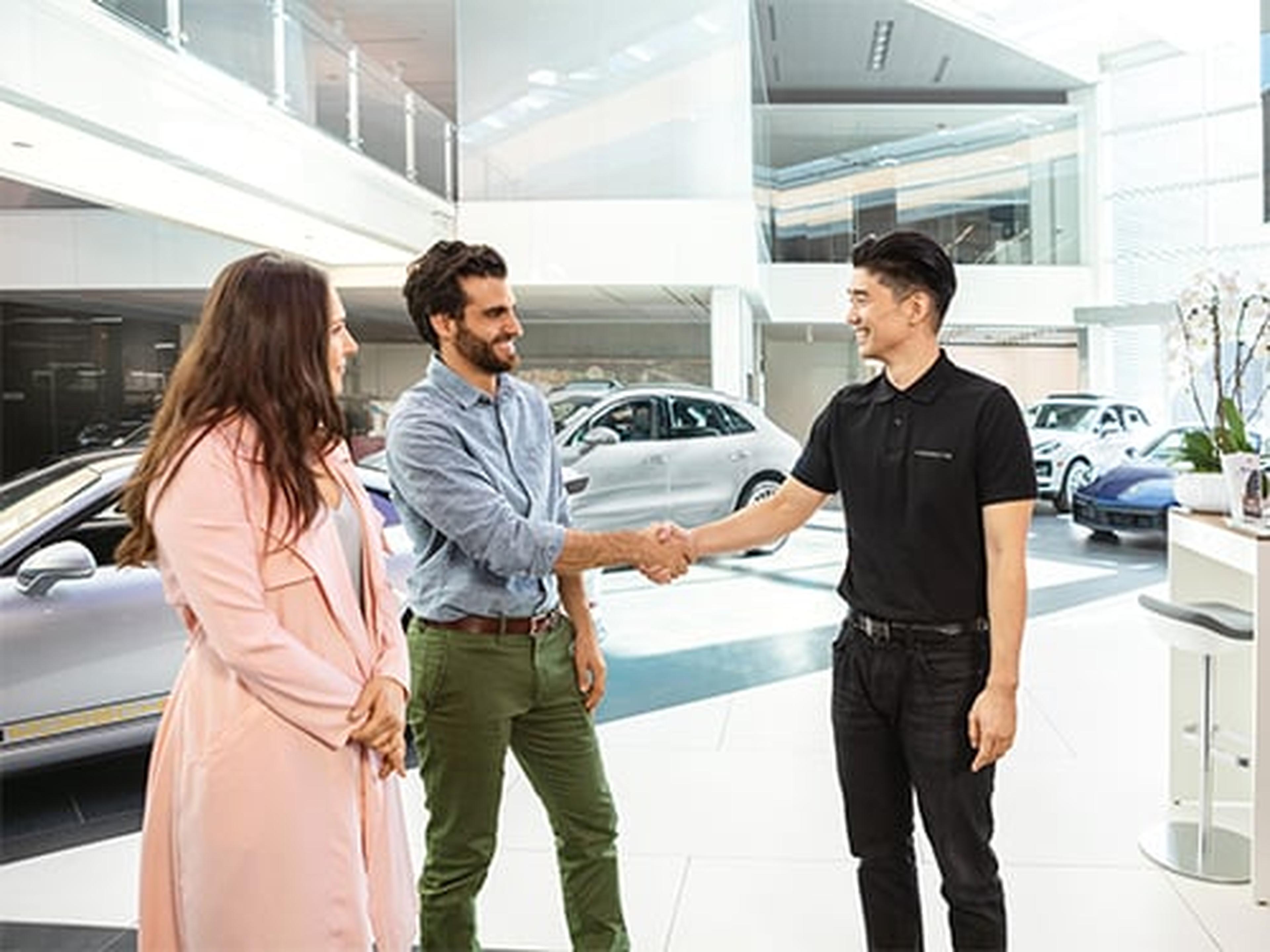 Ein Porsche Servicemitarbeiter begrüsst Kunden im Porsche Zentrum.