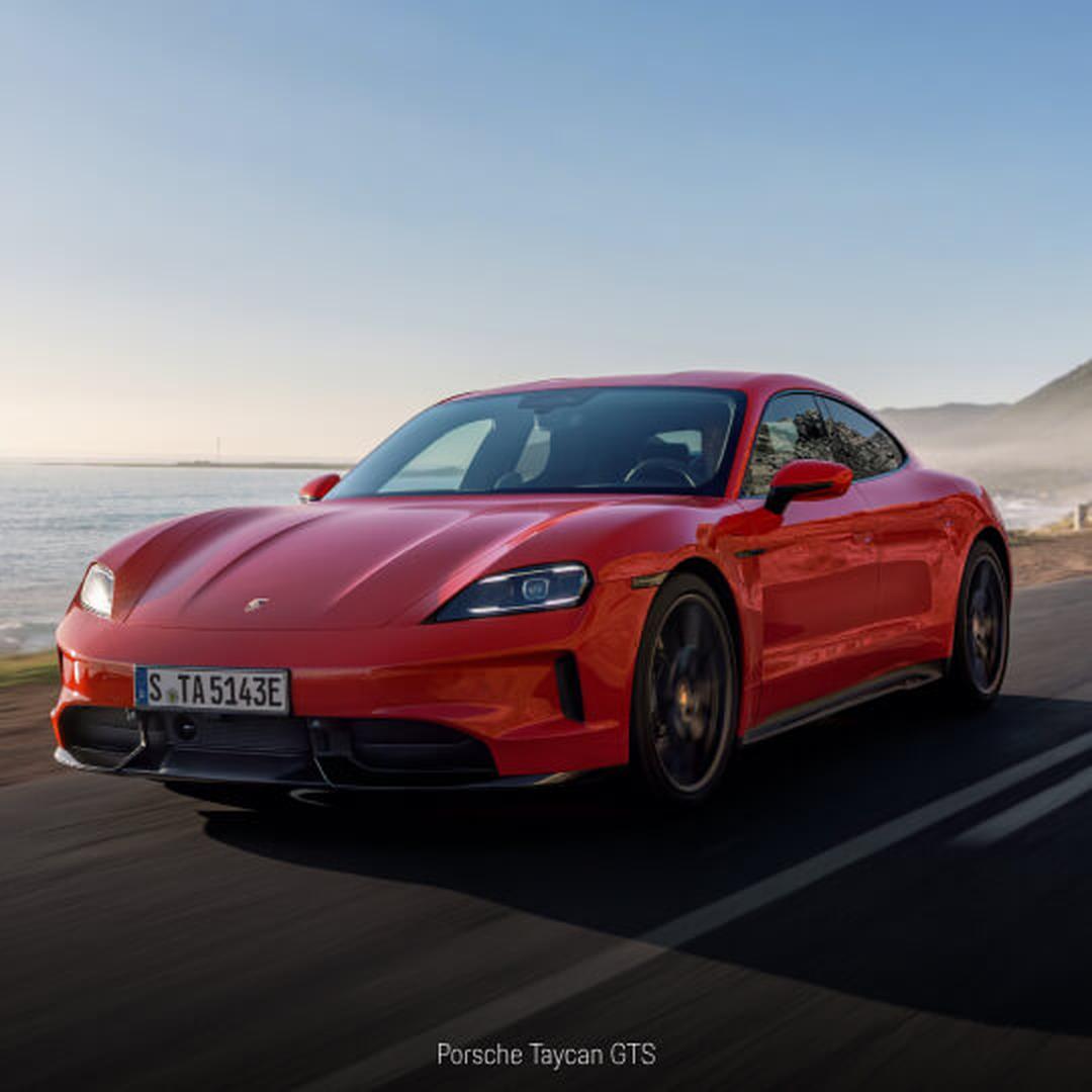 Three-quarter front view of a Porsche Taycan GTS in Red driving along a coastal highway.