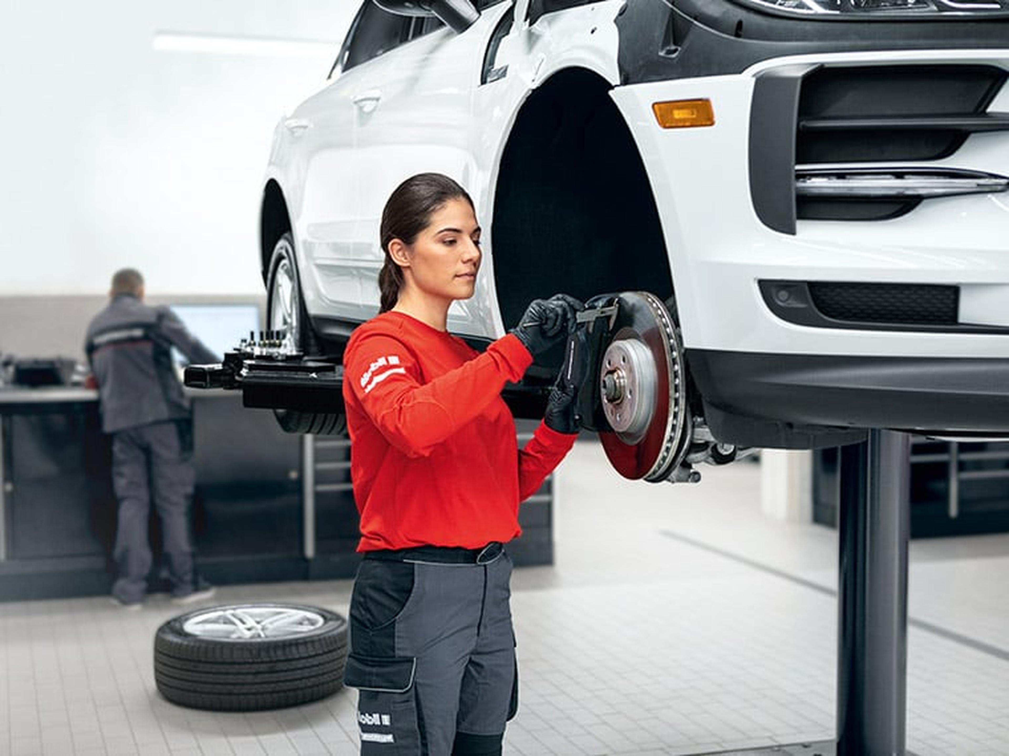 Eine Technikerin schraubt an einem Porsche
