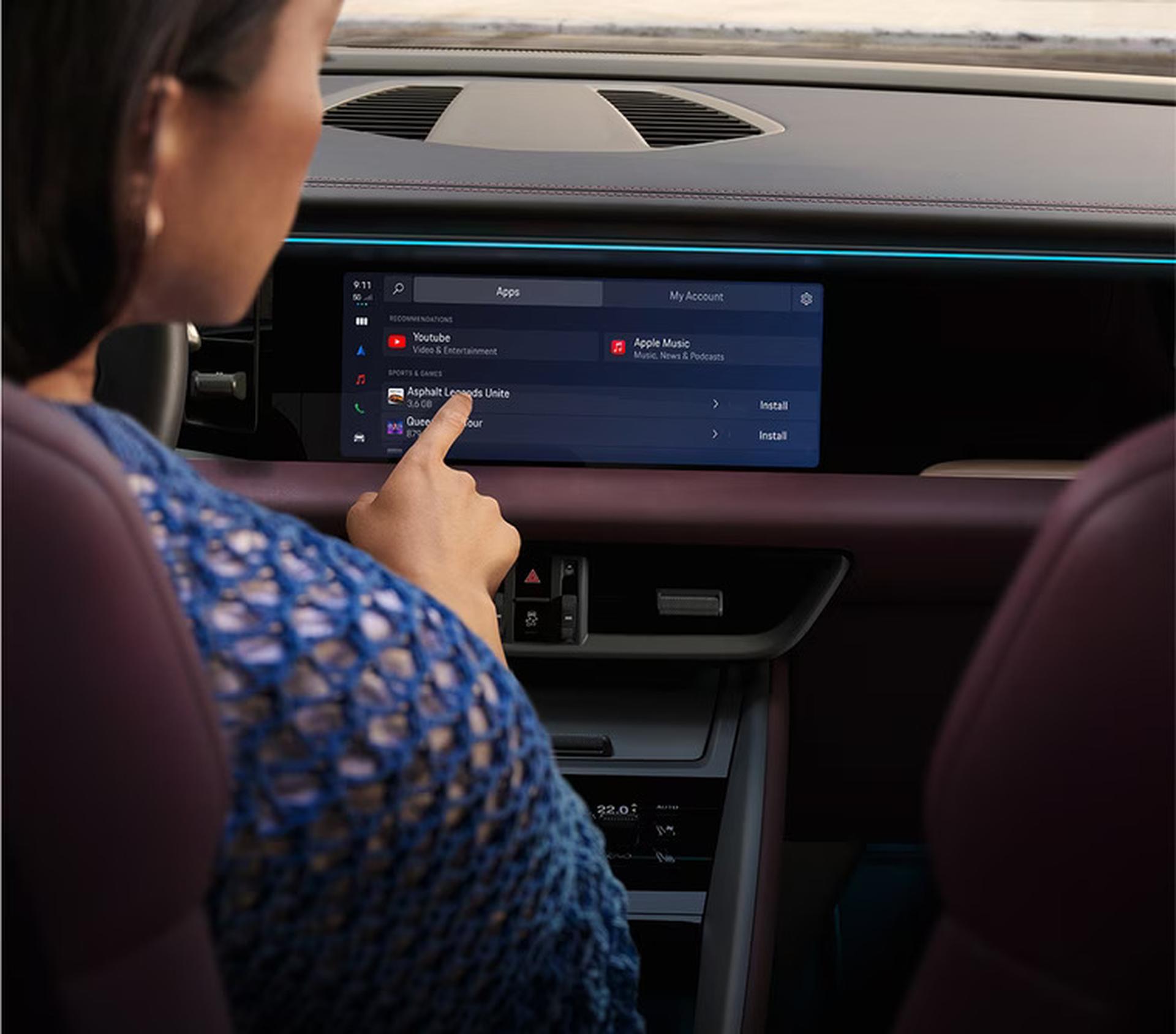 a woman in a 2027 porsche macan electric using the touchscreen on the infotainment system
