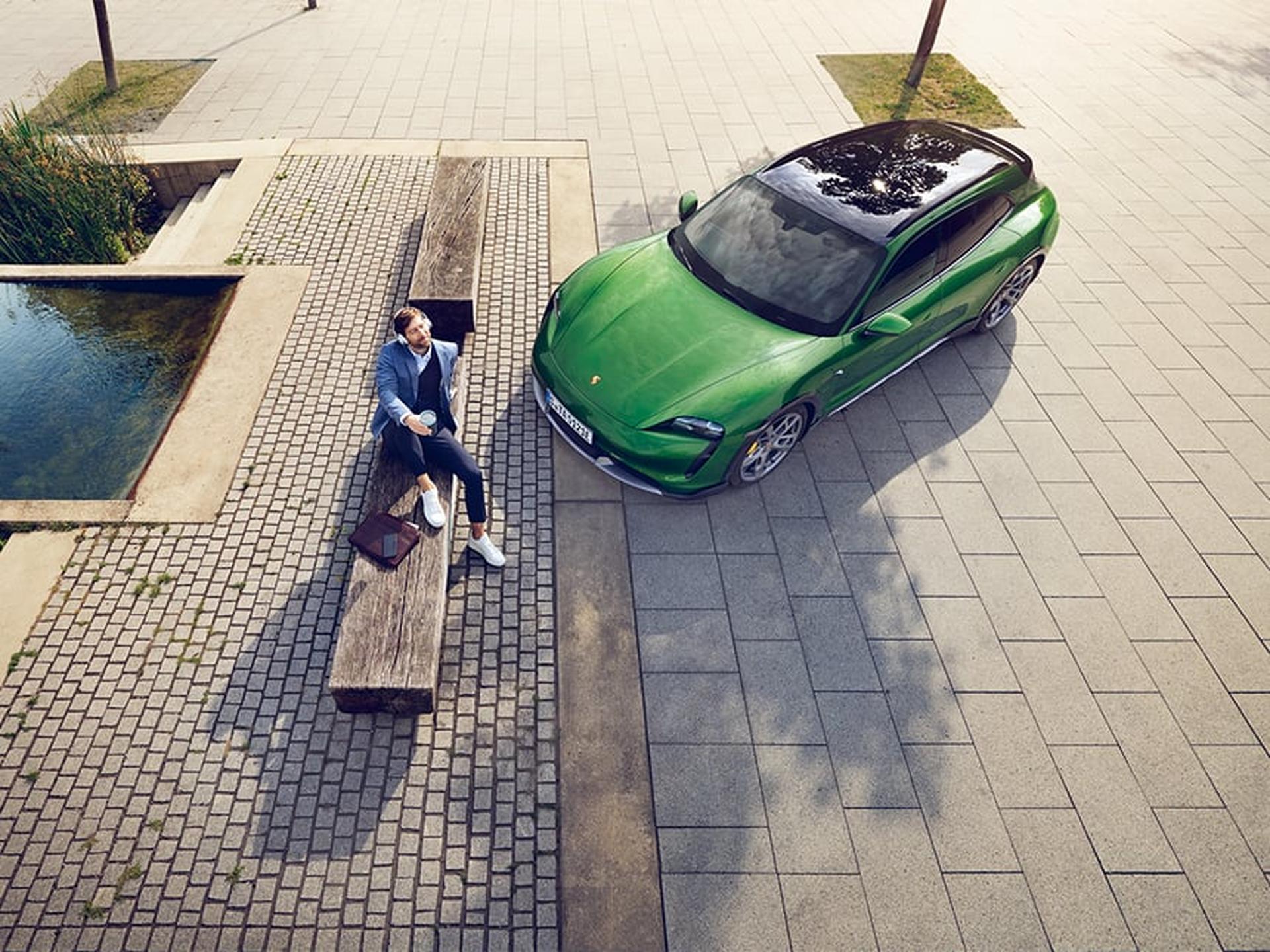 Ein Porsche Kunde geniesst die Sonne neben seinem Porsche Sportwagen.