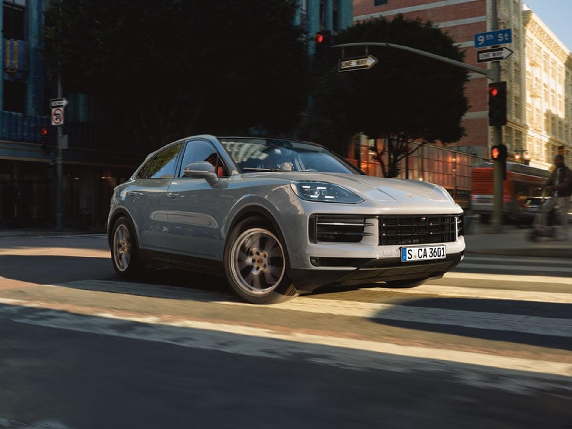 Grey Cayenne turning corner in urban environment.