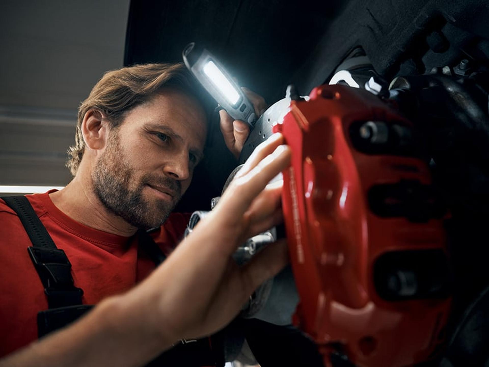 Ein Porsche Service Techniker überprüft einen Porsche Sportwagen.