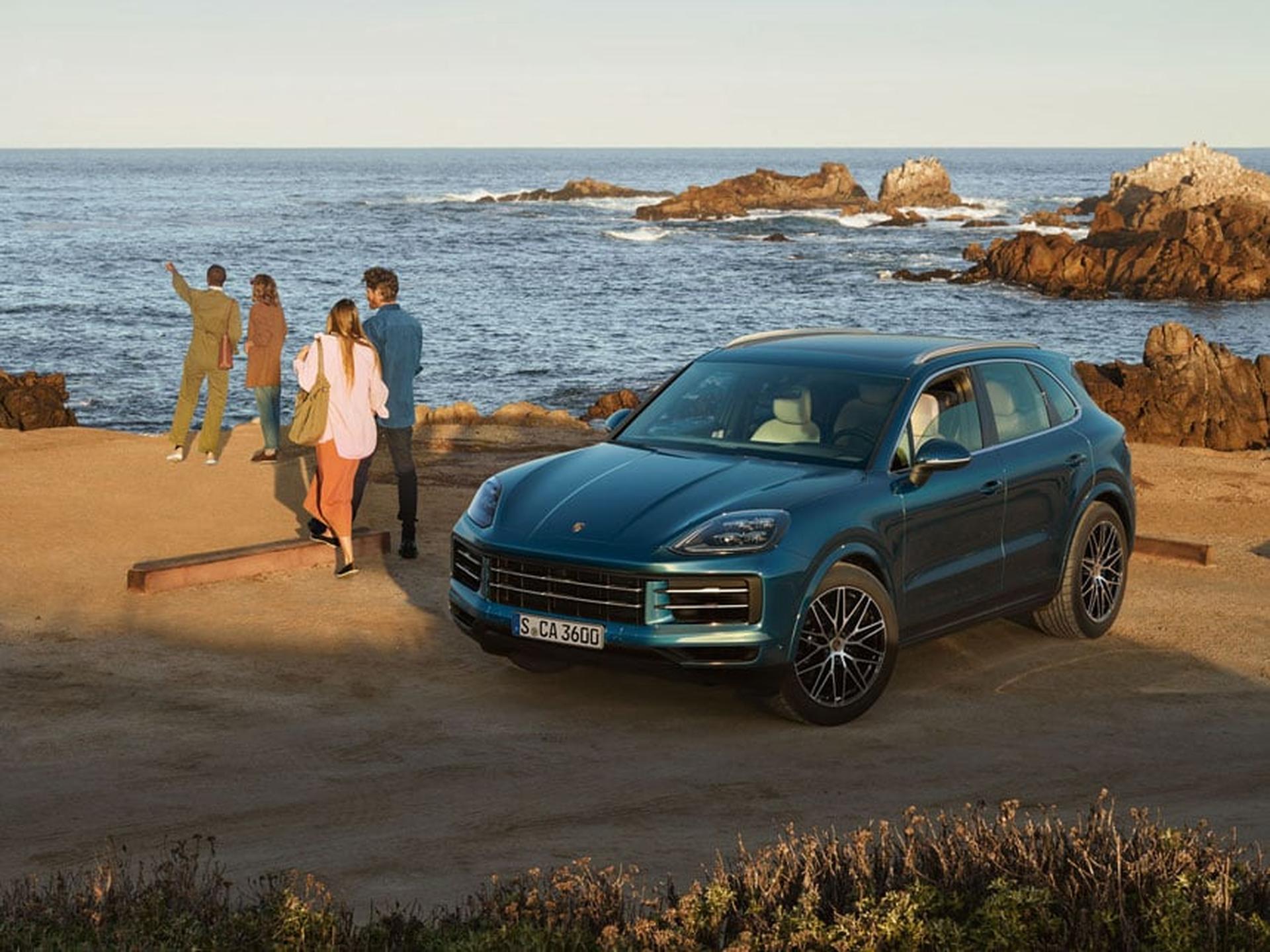 Family standing by blue Cayenne parked next to the ocean.