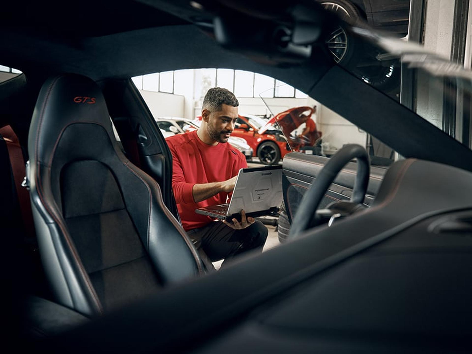 Ein Porsche Service Techniker prüft den Innenraum eines Porsche Sportwagens.