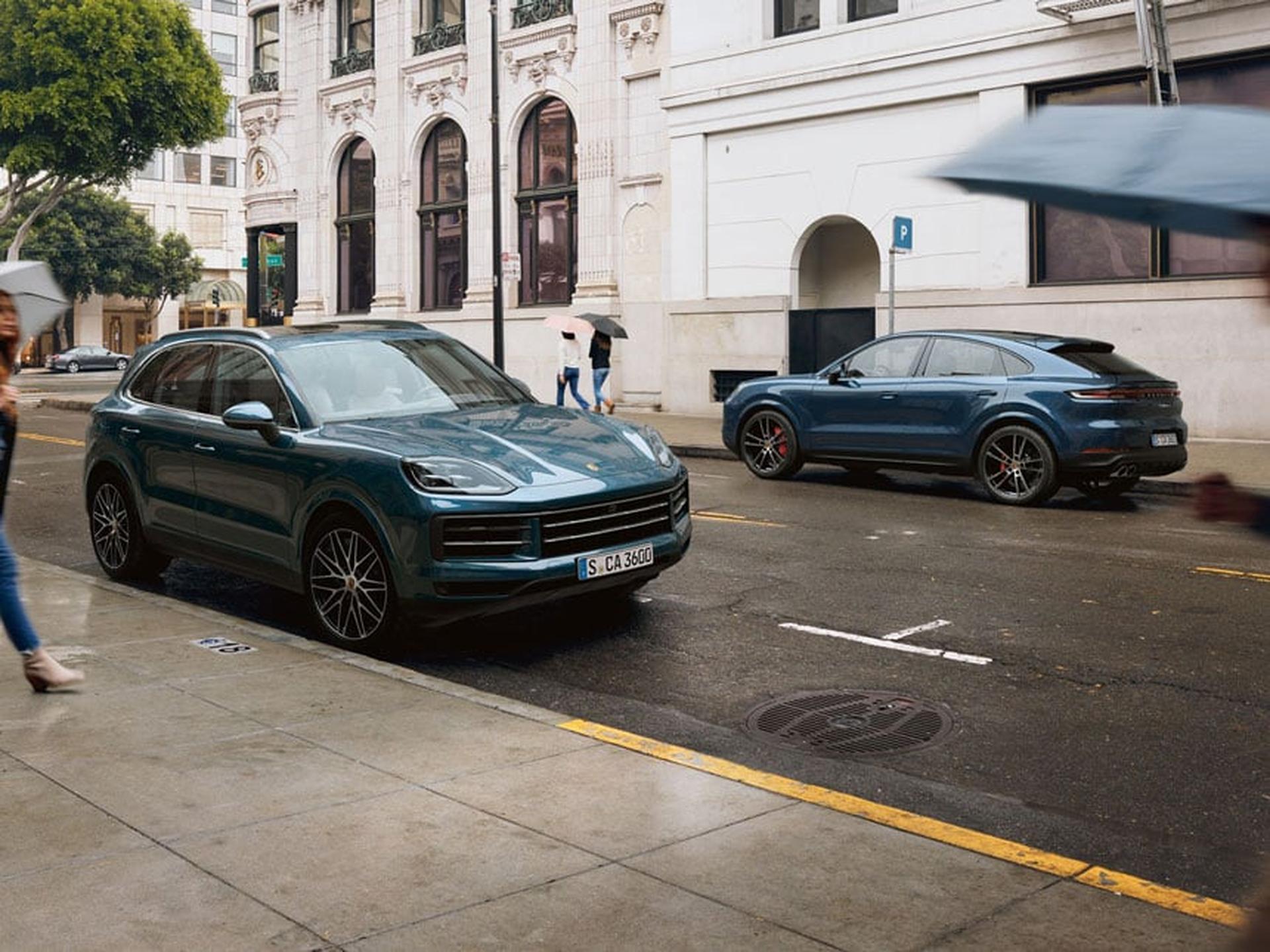 Two blue Cayenne parked across a road in urban environment.