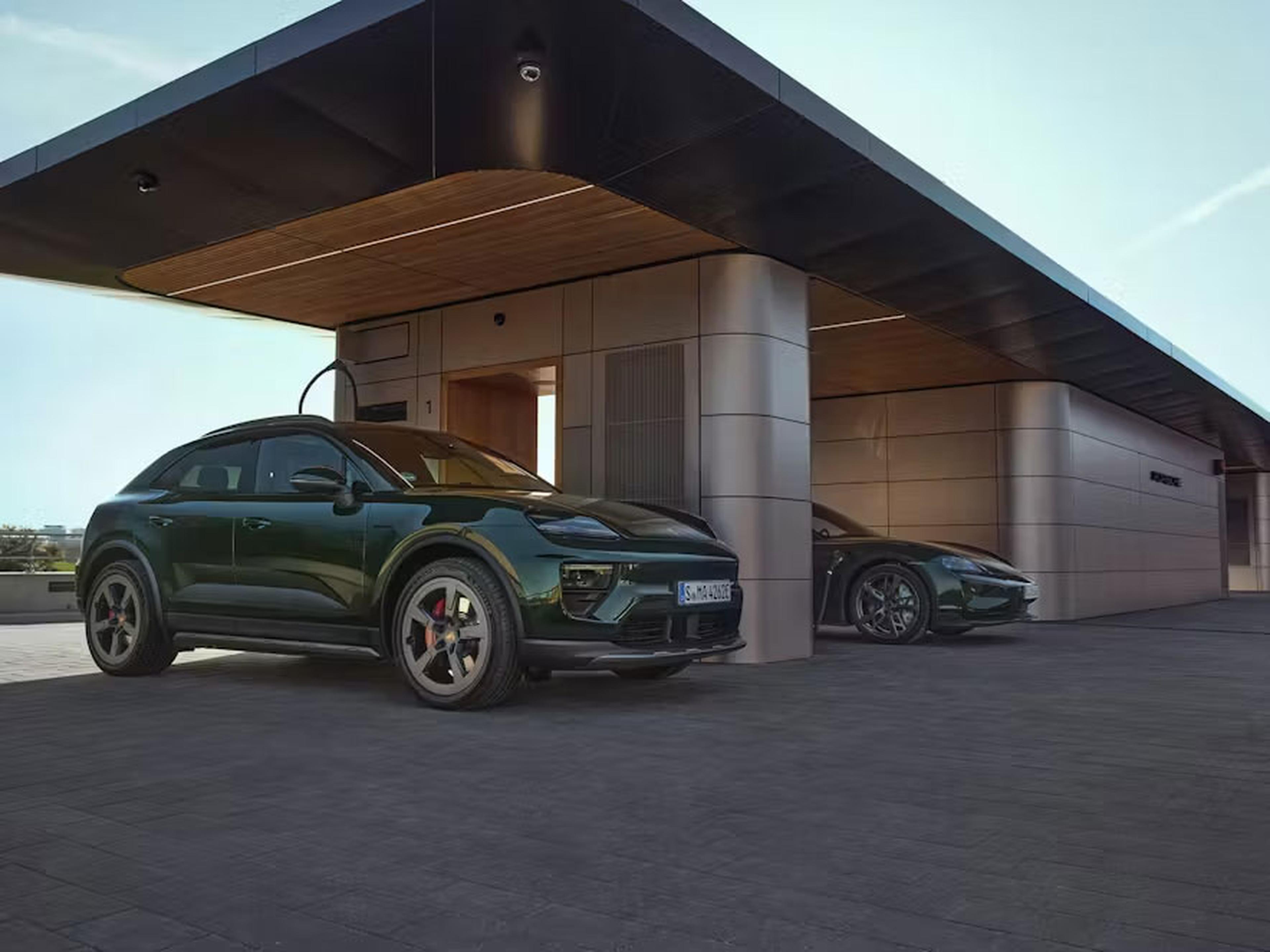 Zwei elegante, grüne Elektroautos, geparkt unter einem modernen Gebäude mit Ladestation, vor einem klaren blauen Himmel.