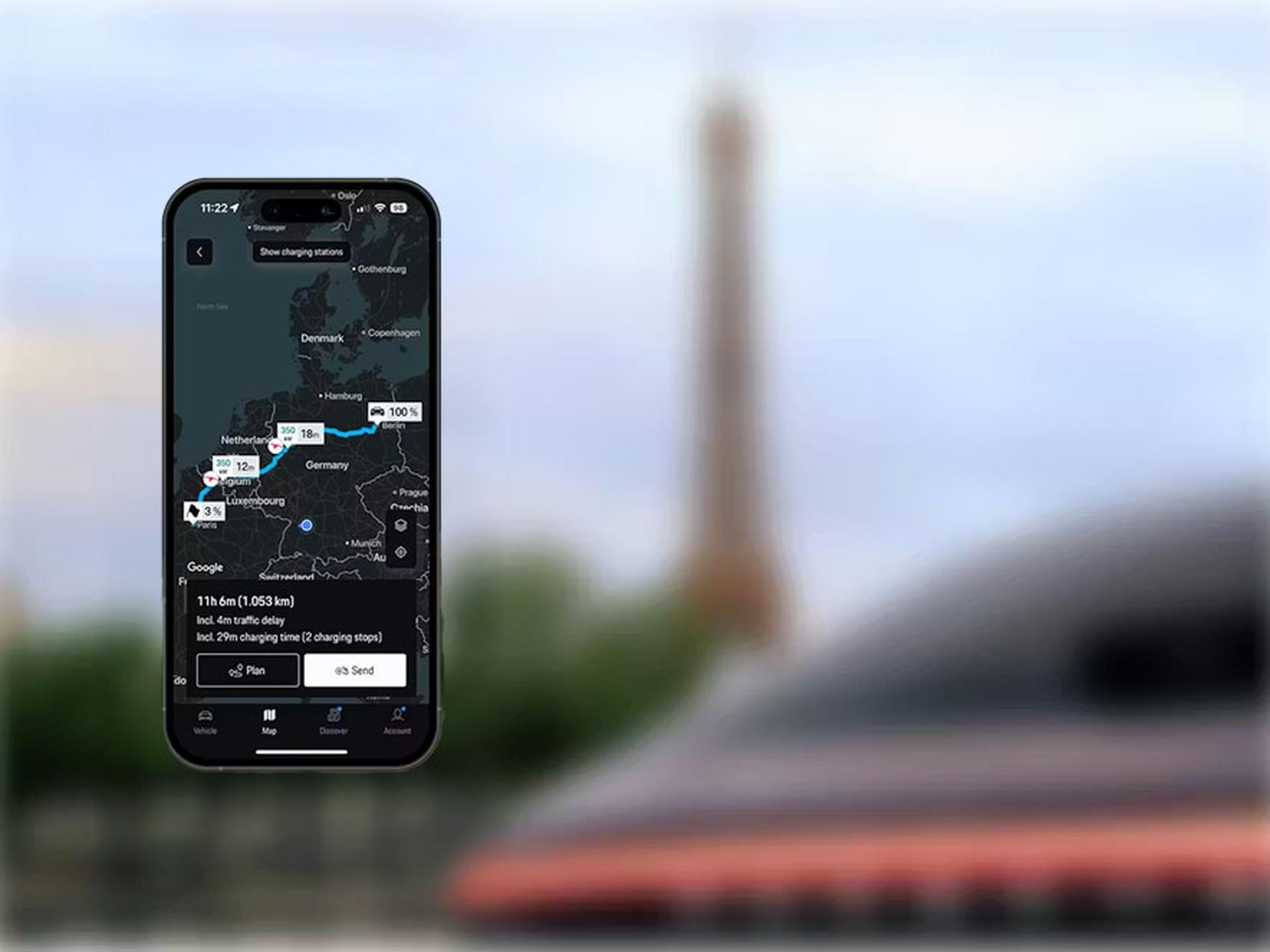 Smartphone, das eine Routenkarte von den Niederlanden nach Frankreich anzeigt, mit dem Eiffelturm im unscharfen Hintergrund.
