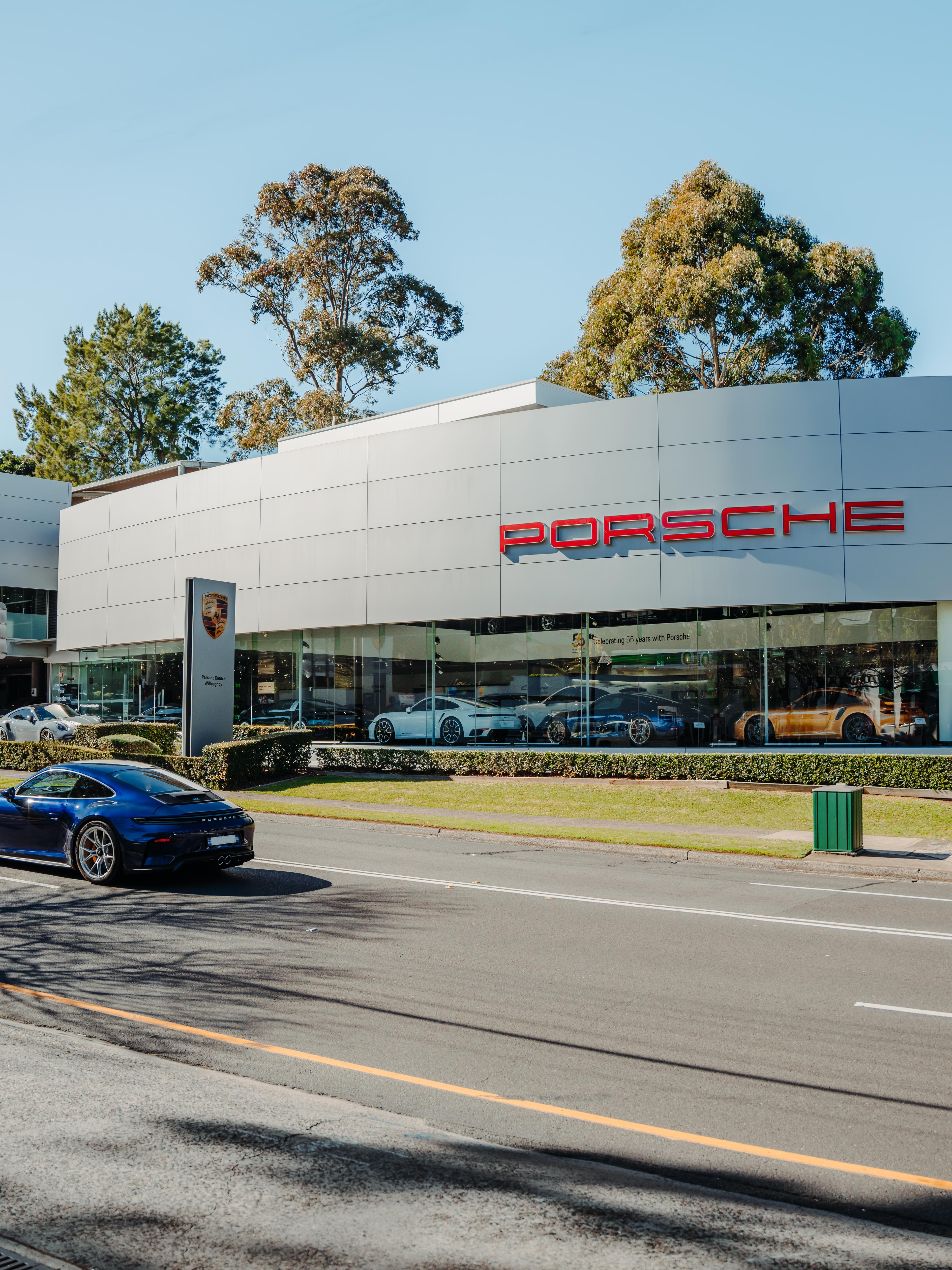 Exterior view of Porsche Centre Willoughby, showcasing the dealership’s modern architectural design, glass façade and Porsche branding.