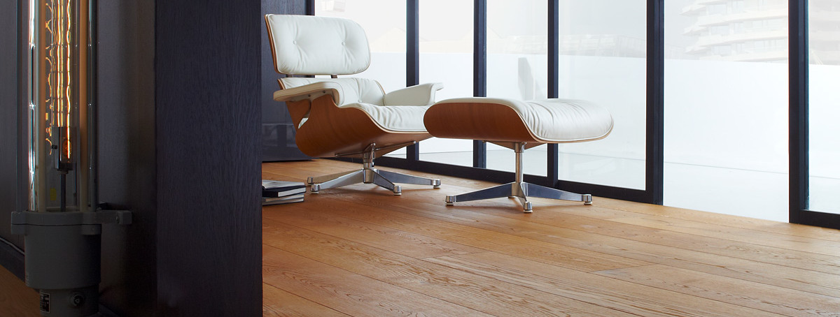 Lounge chair and ottoman on warm oak strip parquet in a bright room.
