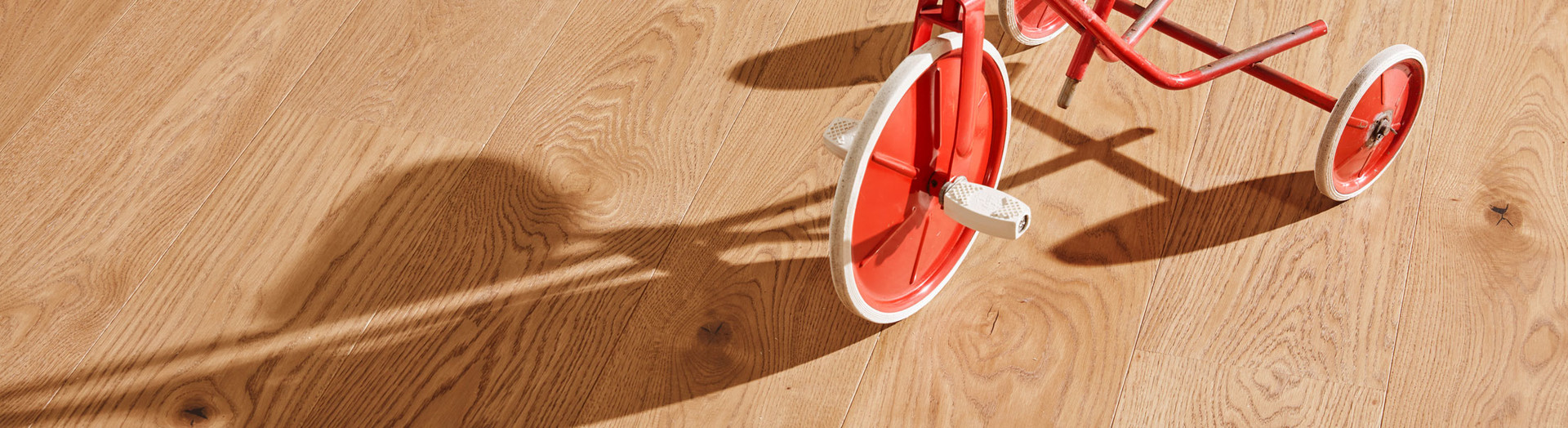 Close-up of oak strip parquet with natural knots and a red wheel detail.