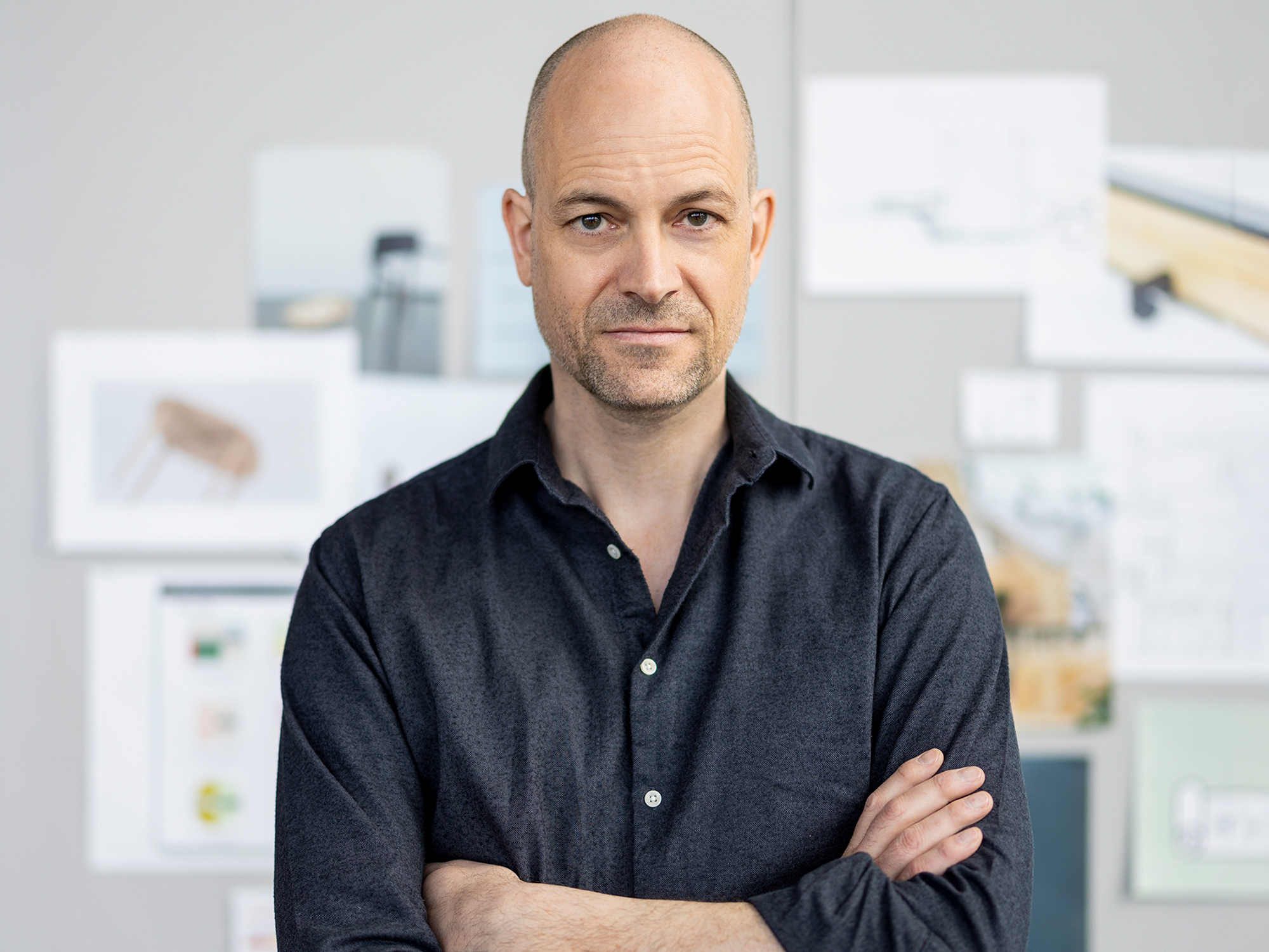 Portrait of designer Stephan Hürlemann with arms crossed, standing in a studio setting.