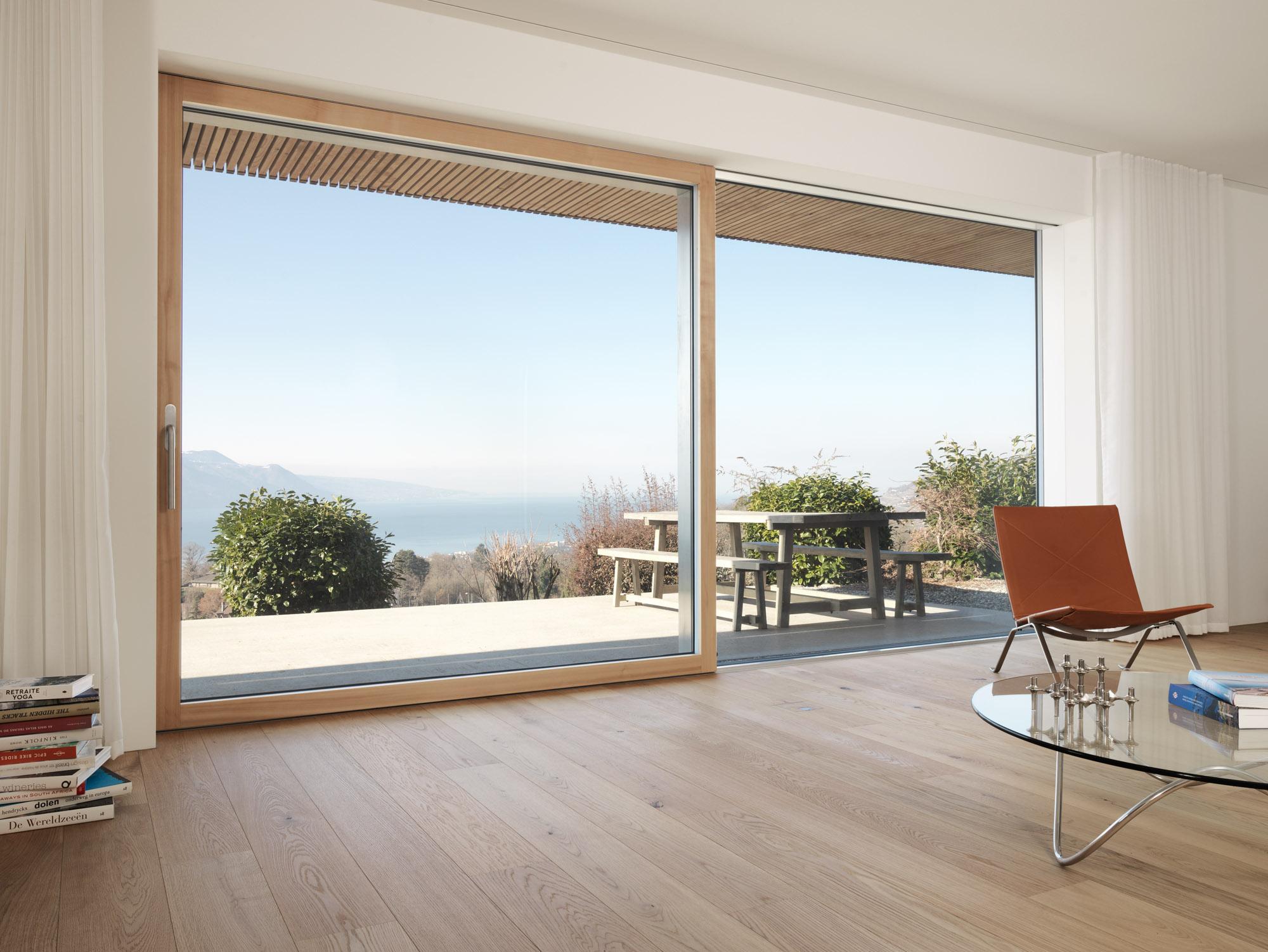 Floor-to-ceiling window with terrace view above light oak strip parquet flooring.