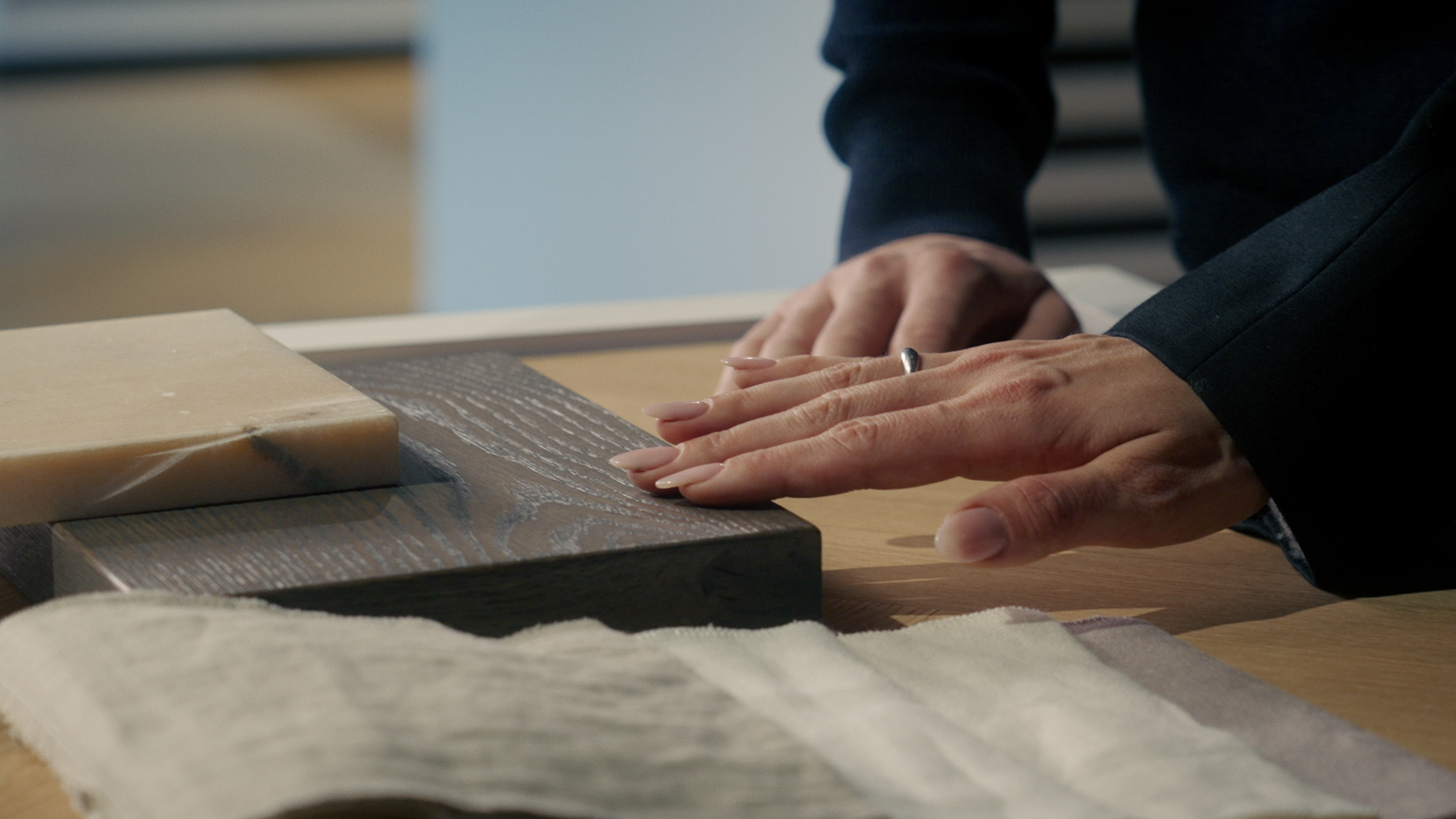 Zwei Personen in einem Showroom betrachten Parkettmuster an einem Präsentationstisch und diskutieren die Auswahl von Bauwerk-Produkten.