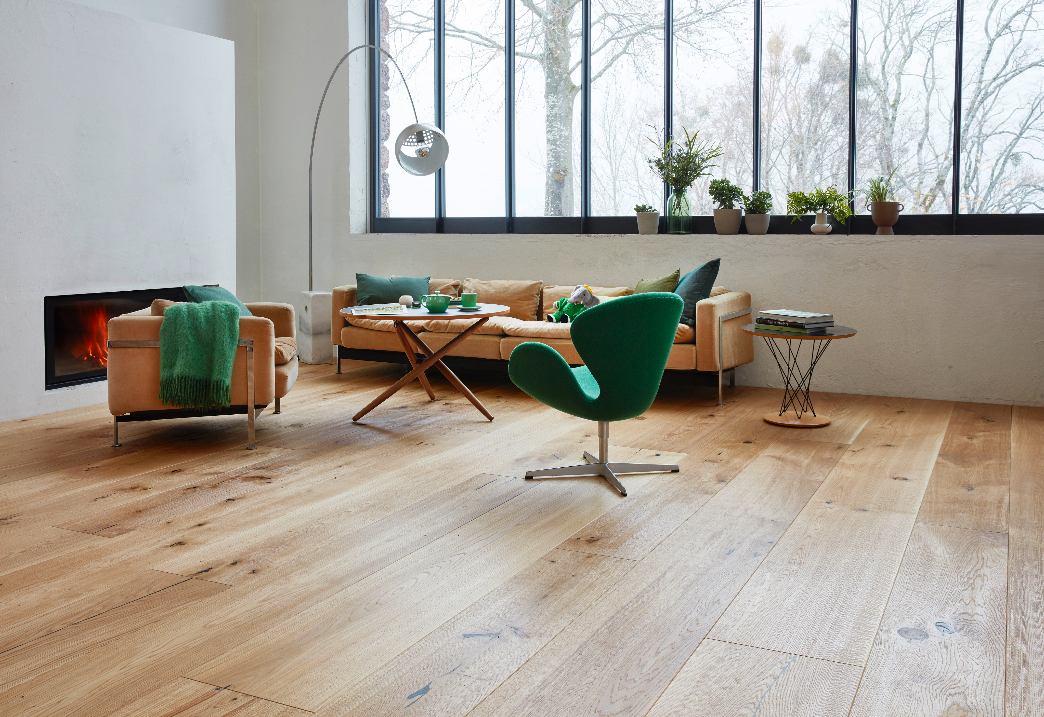 Living room with light oak strip parquet, green chair and sofa by large windows.