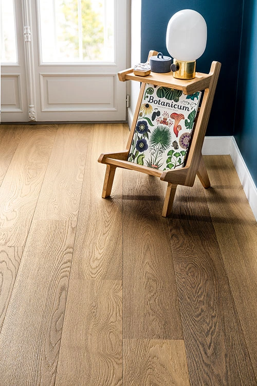 Wooden lounge chair with patterned cushion on light oak strip parquet in a modern room.