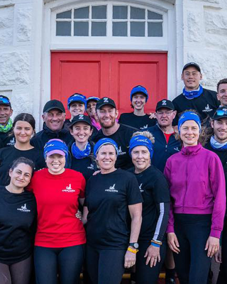 "Group photo of team members gathered outside a white lighthouse with a red door, representing Scott Bader's community initiatives." [G]