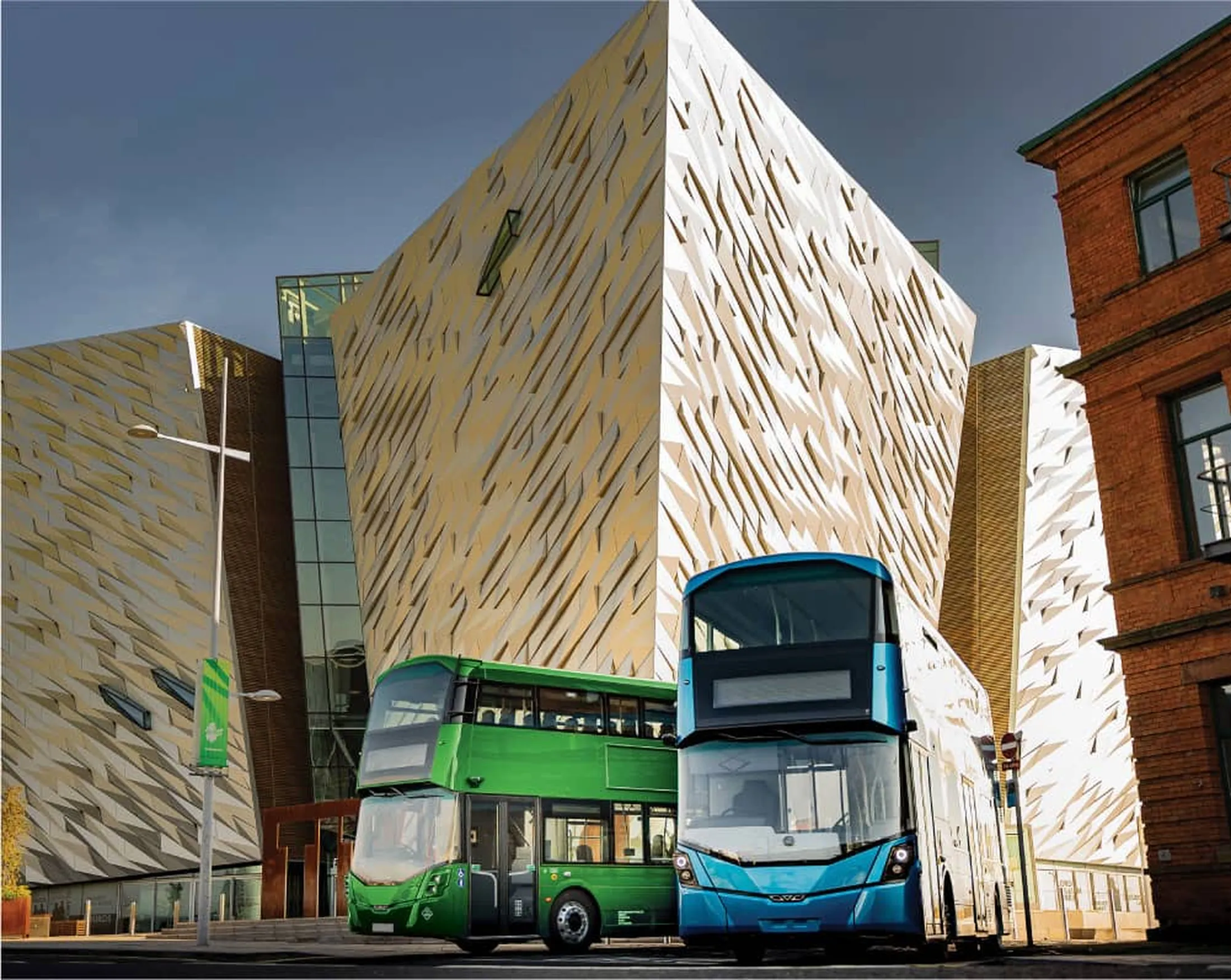 "Modern buses in front of the Titanic Belfast museum with its distinctive geometric composite facade architecture" [G]