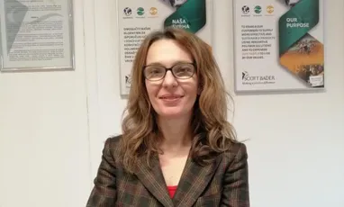 "Professional in a plaid blazer standing in front of Scott Bader informational posters about composites and adhesives" [G]