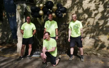 "Team in bright green shirts at outdoor event with black and gold balloons, representing Scott Bader company activities" [G]