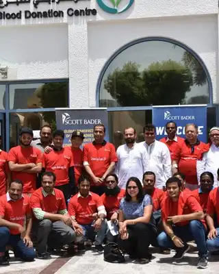 "Scott Bader team in red shirts gathered outside Dubai Blood Donation Centre, supporting community healthcare initiatives" [G]