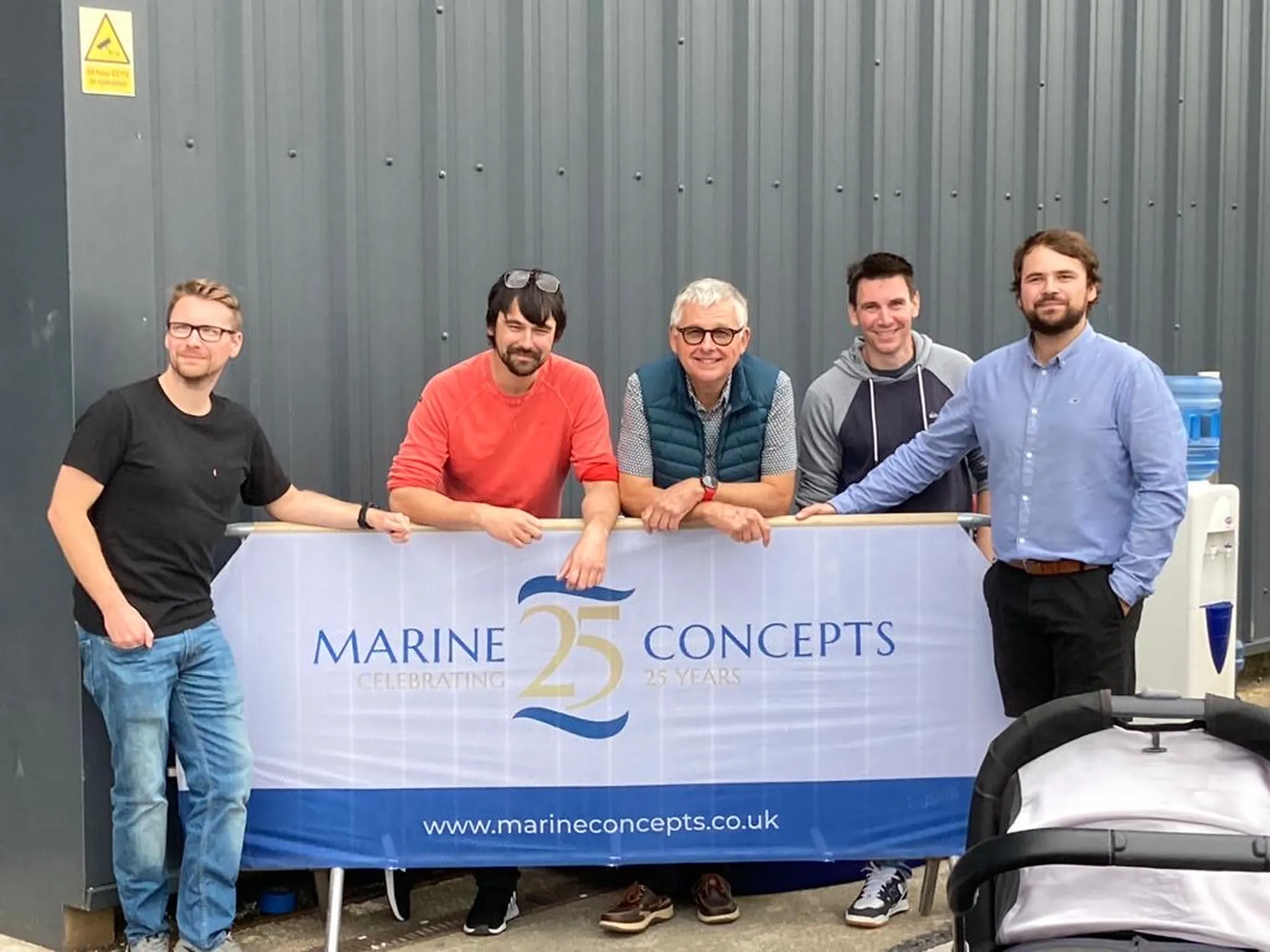 "Group standing with Marine Concepts 25th anniversary banner, showcasing Scott Bader composites and gelcoats for marine applications" [G]