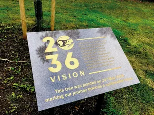 "Commemorative plaque marking '2036 Vision' with newly planted tree on grassy area" [G]
