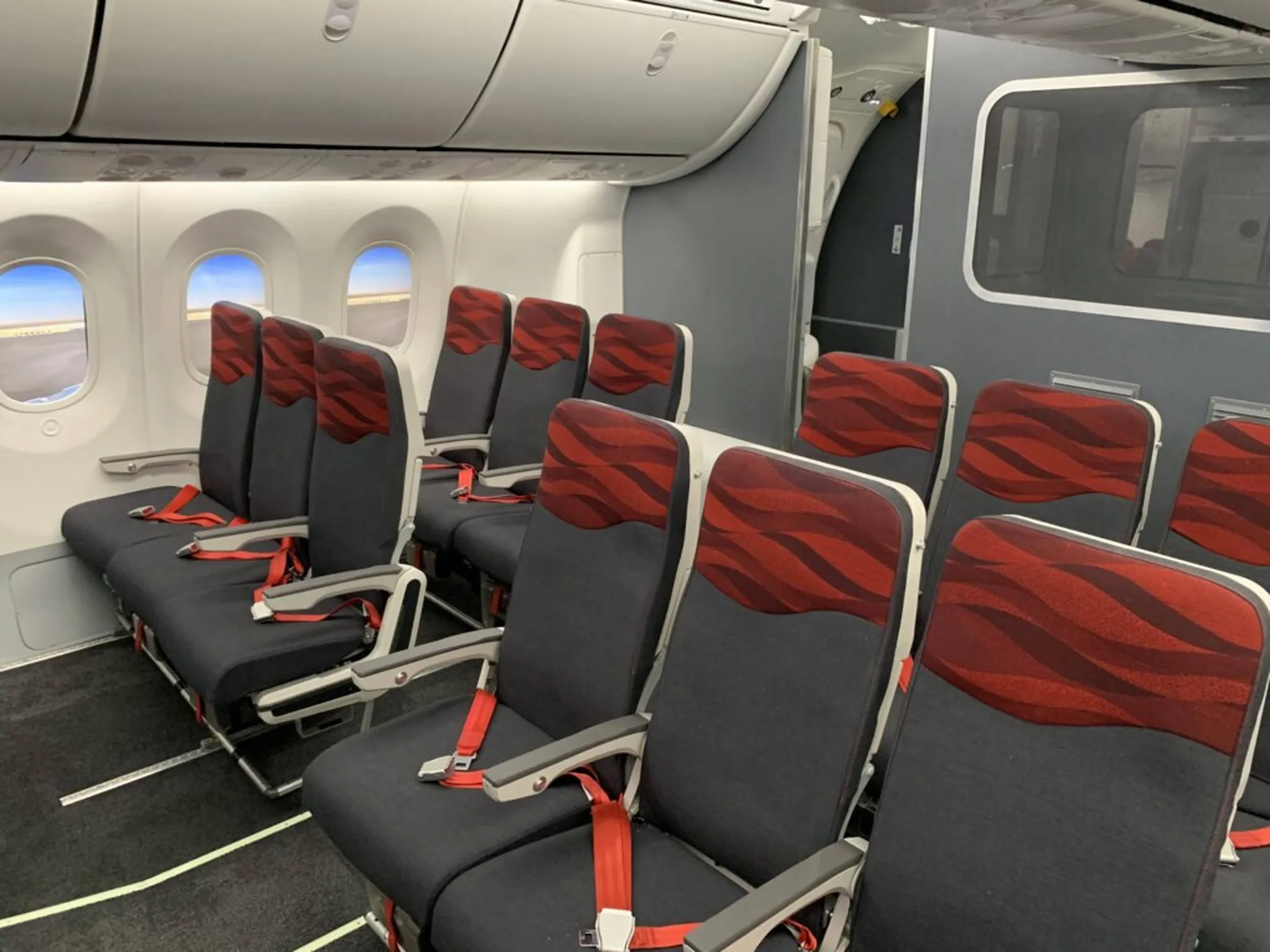 Aircraft interior showing rows of red and gray passenger seats with Scott Bader composites used in aerospace applications [G]