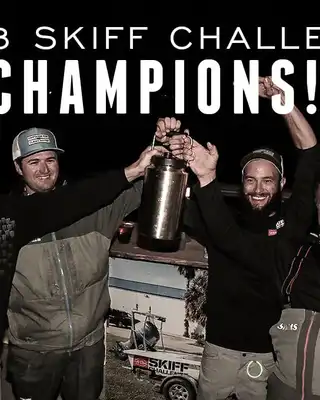 "2018 Skiff Challenge Champions celebrating victory with trophy at night event, supported by Scott Bader composites" [G]
