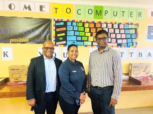 Image of three people at a school computer lab donation event supported by Scott Bader community initiatives. [G]