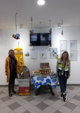 "Office display with bee-themed decorations and refreshment table at Scott Bader, showcasing company certificates on wall" [G]