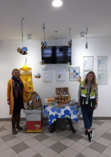 "Office display with bee-themed decorations and refreshment table at Scott Bader, showcasing company certificates on wall" [G]