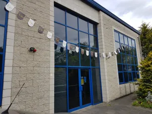 "Modern industrial building exterior with blue-framed windows and decorative bunting at Scott Bader facility" [G]