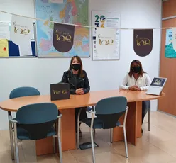 "Office meeting at Scott Bader with branded centenary banners and European map in background" [G]