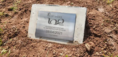 "Scott Bader 100 years commemorative plaque embedded in soil, celebrating a century of excellence in composites and resins" [G]